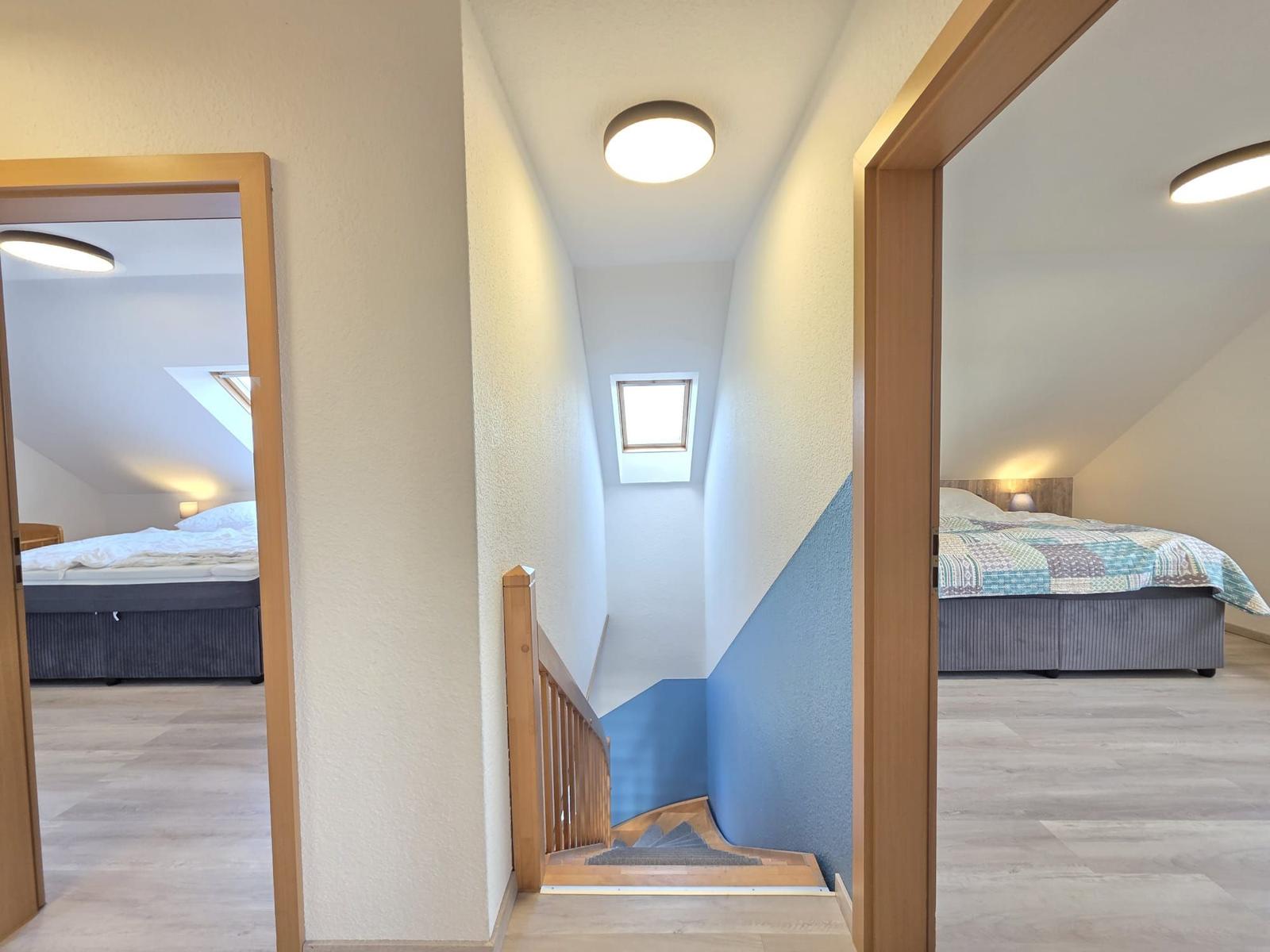 Treppenhaus mit Schlafzimmer links und rechts. Blaue Wand und Dachfenster.