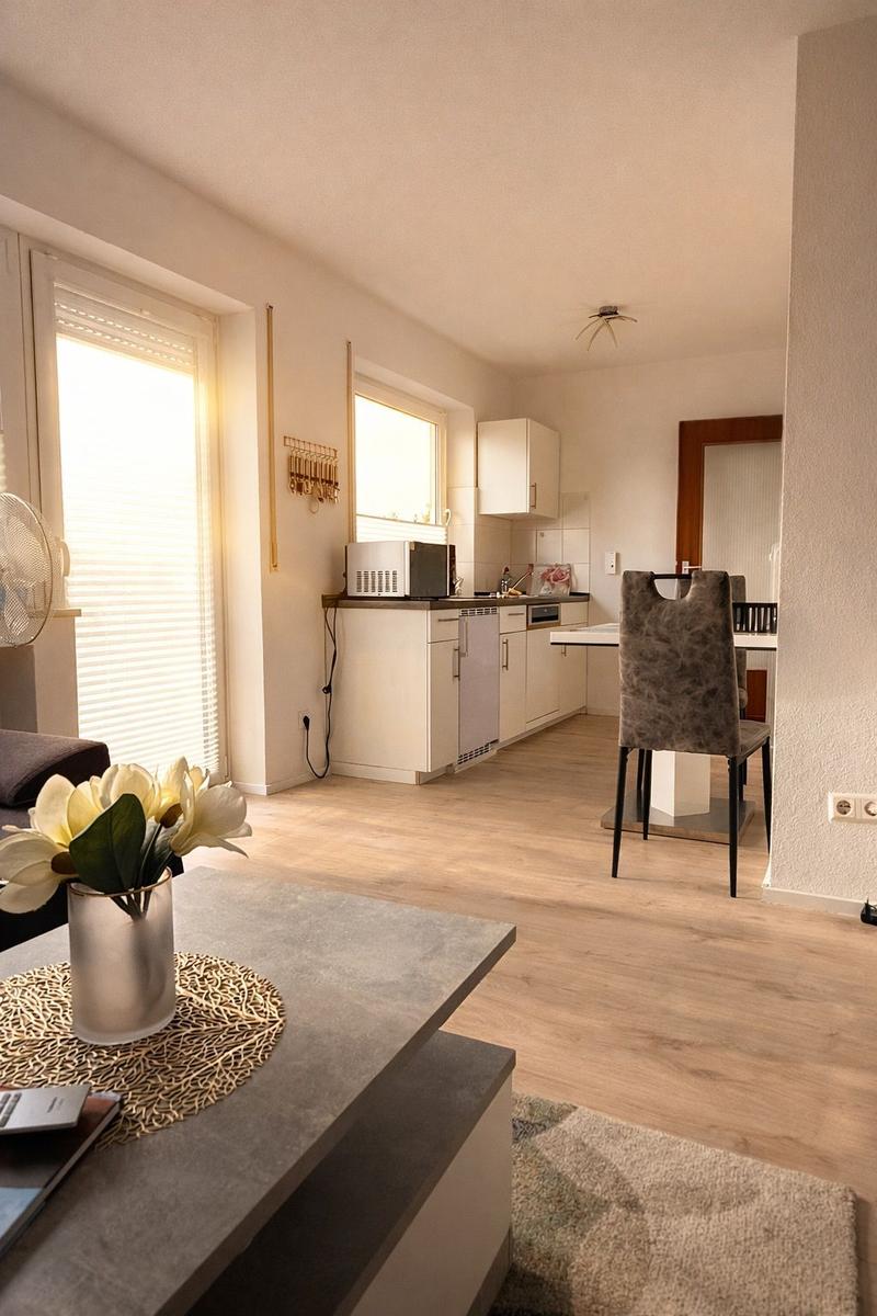 Wohn- und Küchenbereich mit Holzboden, Fenster und Essbereich.
