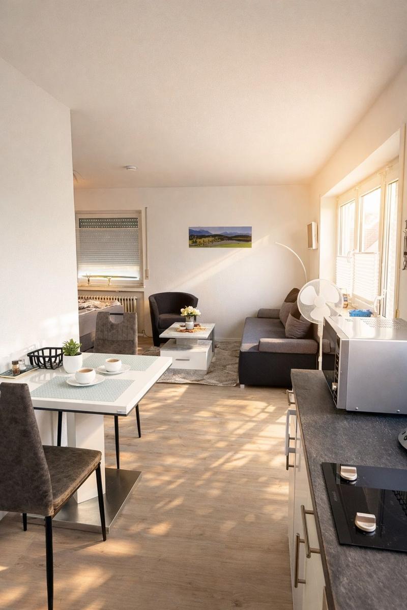 Wohnung mit Essbereich, Sofa und Küchenzeile. Fenster mit Blick auf Landschaft.