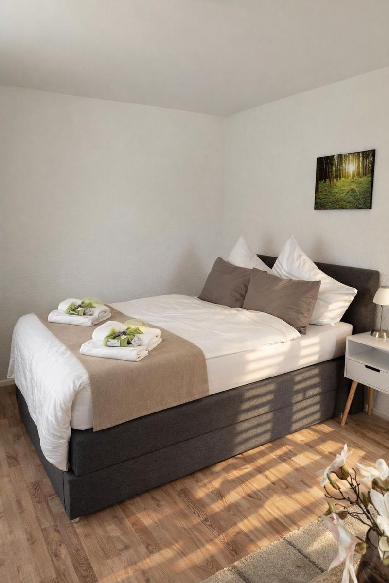 Schlafzimmer mit Bett, Nachttisch und Wandbild.