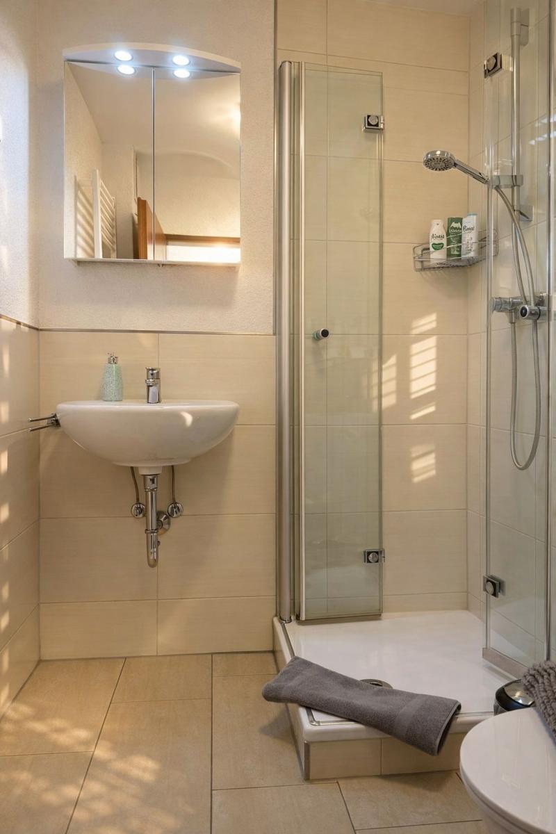 Badezimmer mit Dusche, Waschbecken und Spiegel