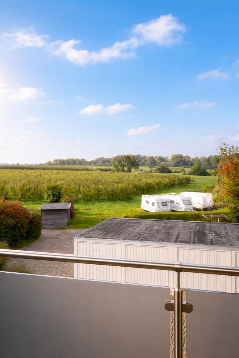 Blick vom Balkon auf Felder und Wohnmobile unter blauem Himmel.
