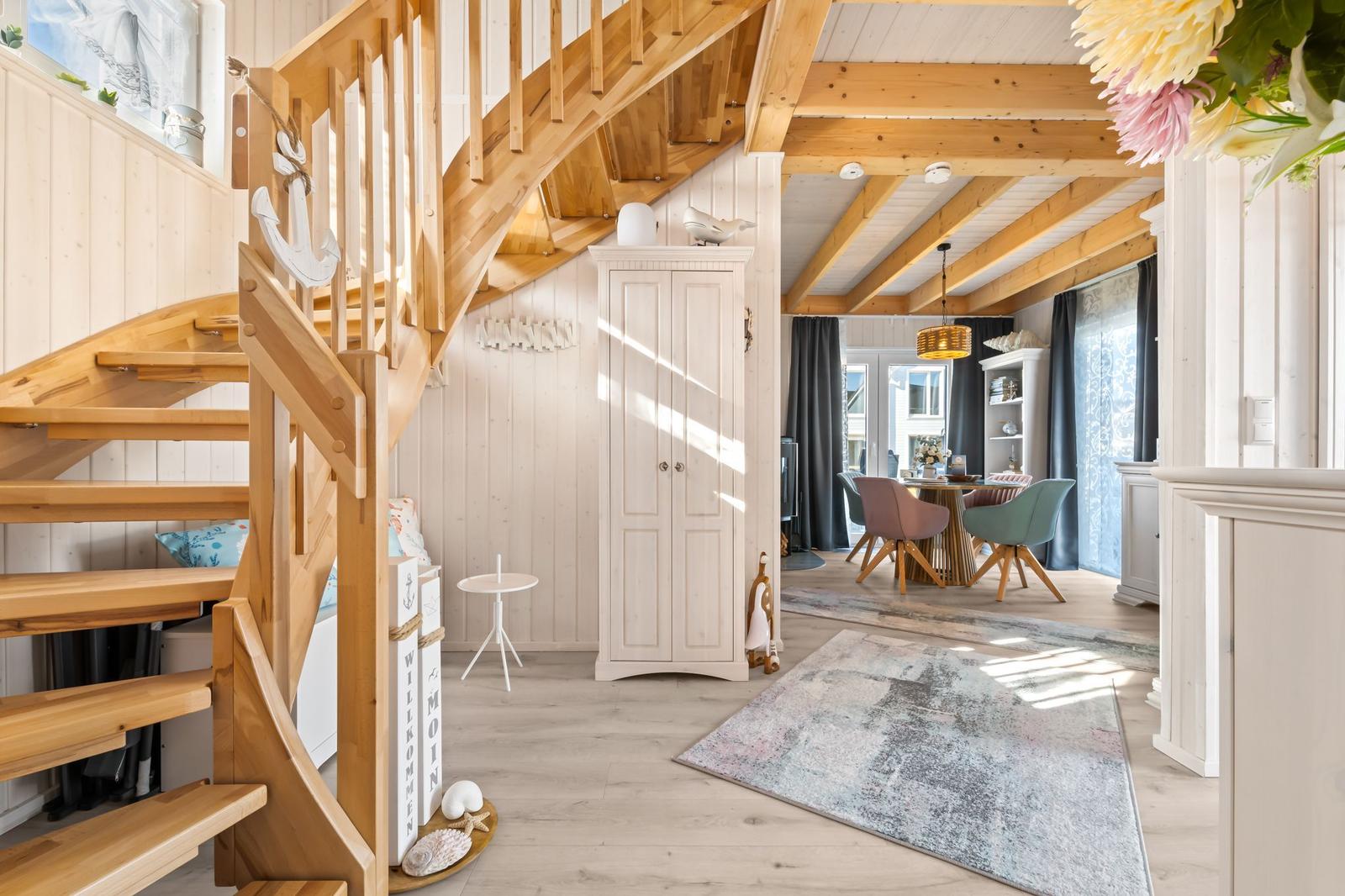 Holztreppe führt zu einer Wohnung mit Essbereich und Holzbalkendecke.