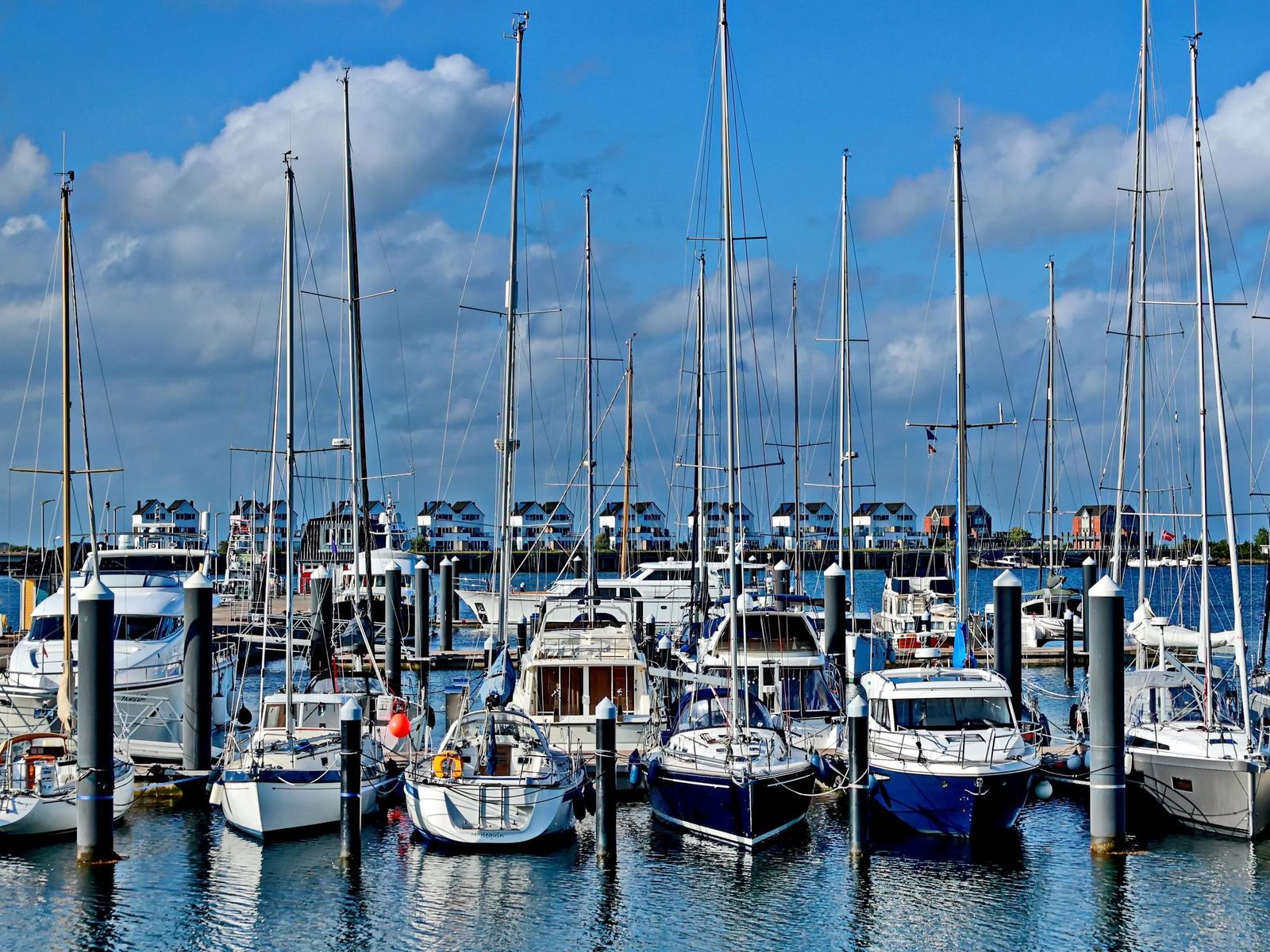 Hafen mit vielen Segelyachten und Motorbooten unter blauem Himmel.