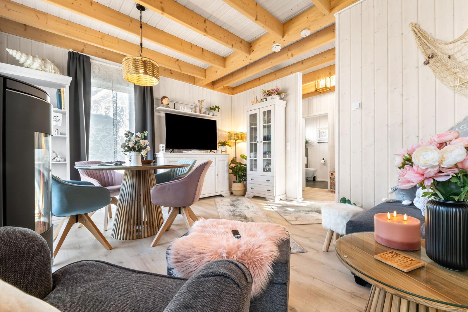 Wohn- und Essbereich mit Holzbalkendecke, TV, Esstisch und Sofa.