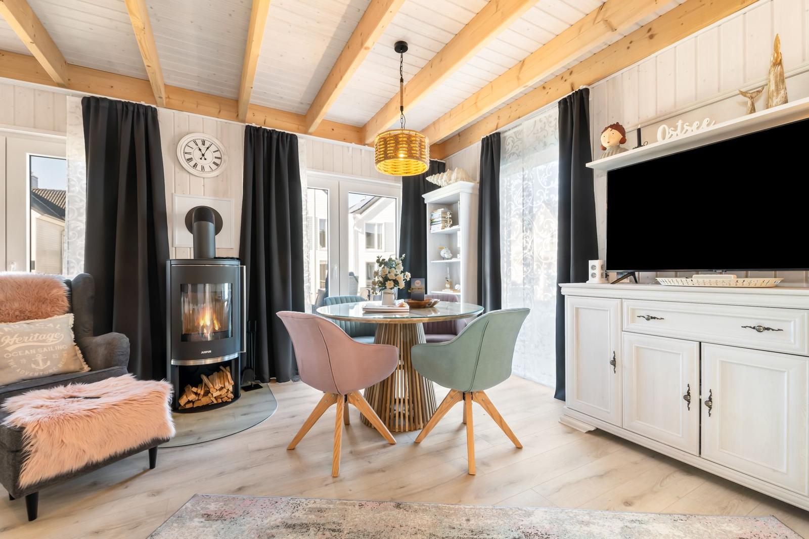 Wohnzimmer mit Kamin, Esstisch und Fernseher. Holzdecke und helles Parkett.