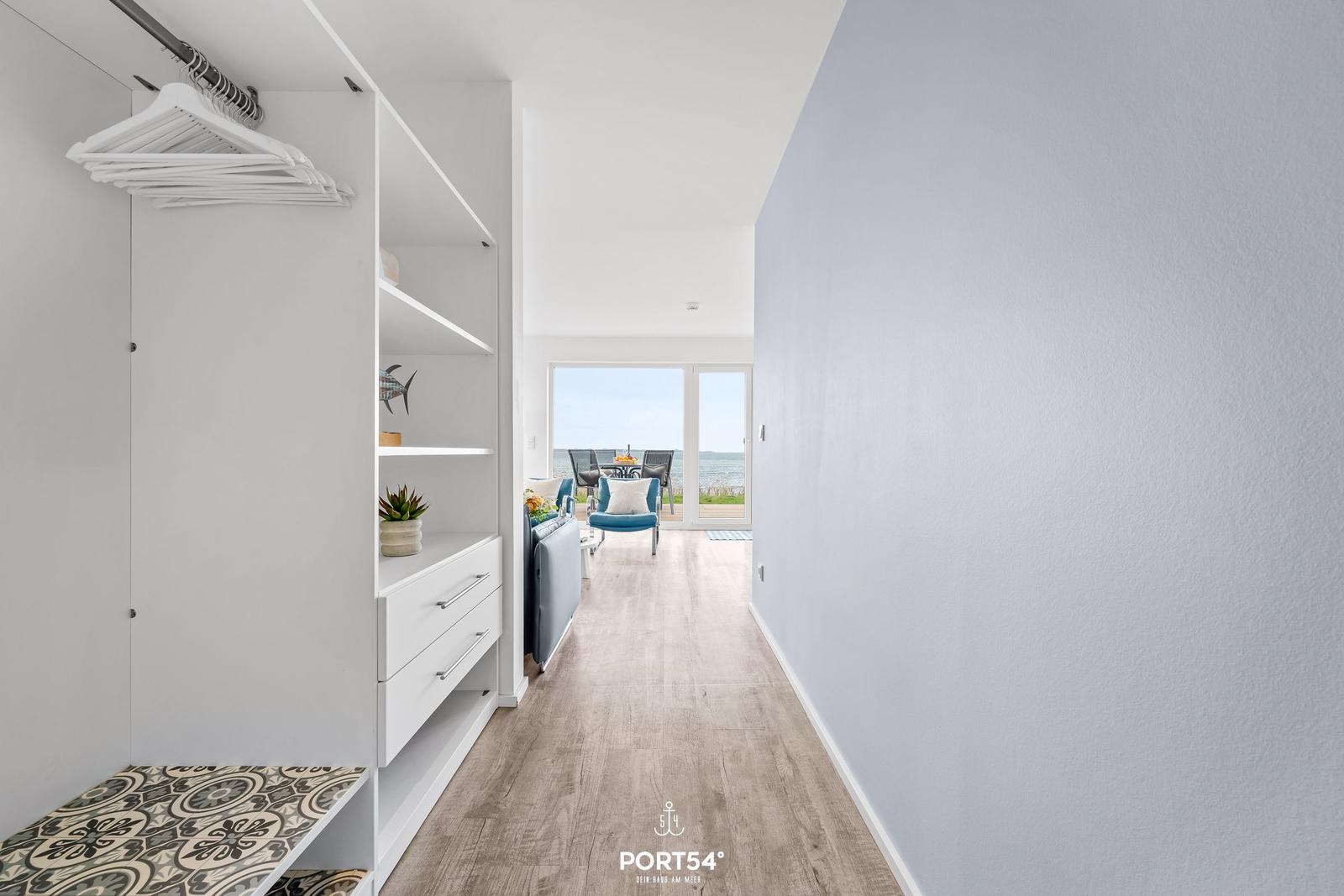 Gewölbter Flur mit Kleiderschrank und Blick auf Terrasse mit Meerblick.