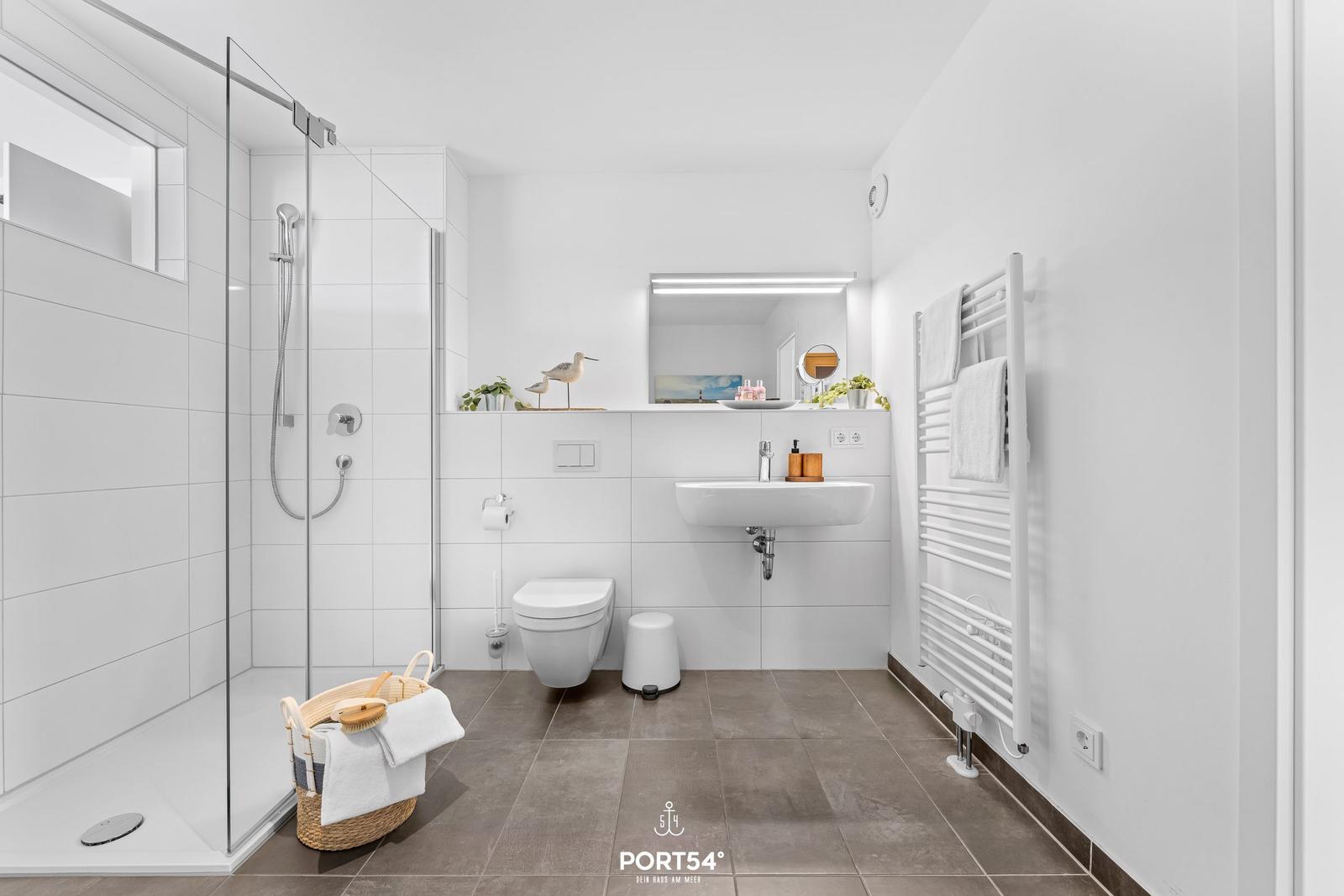 Badezimmer mit Dusche, Waschbecken und Heizkörper