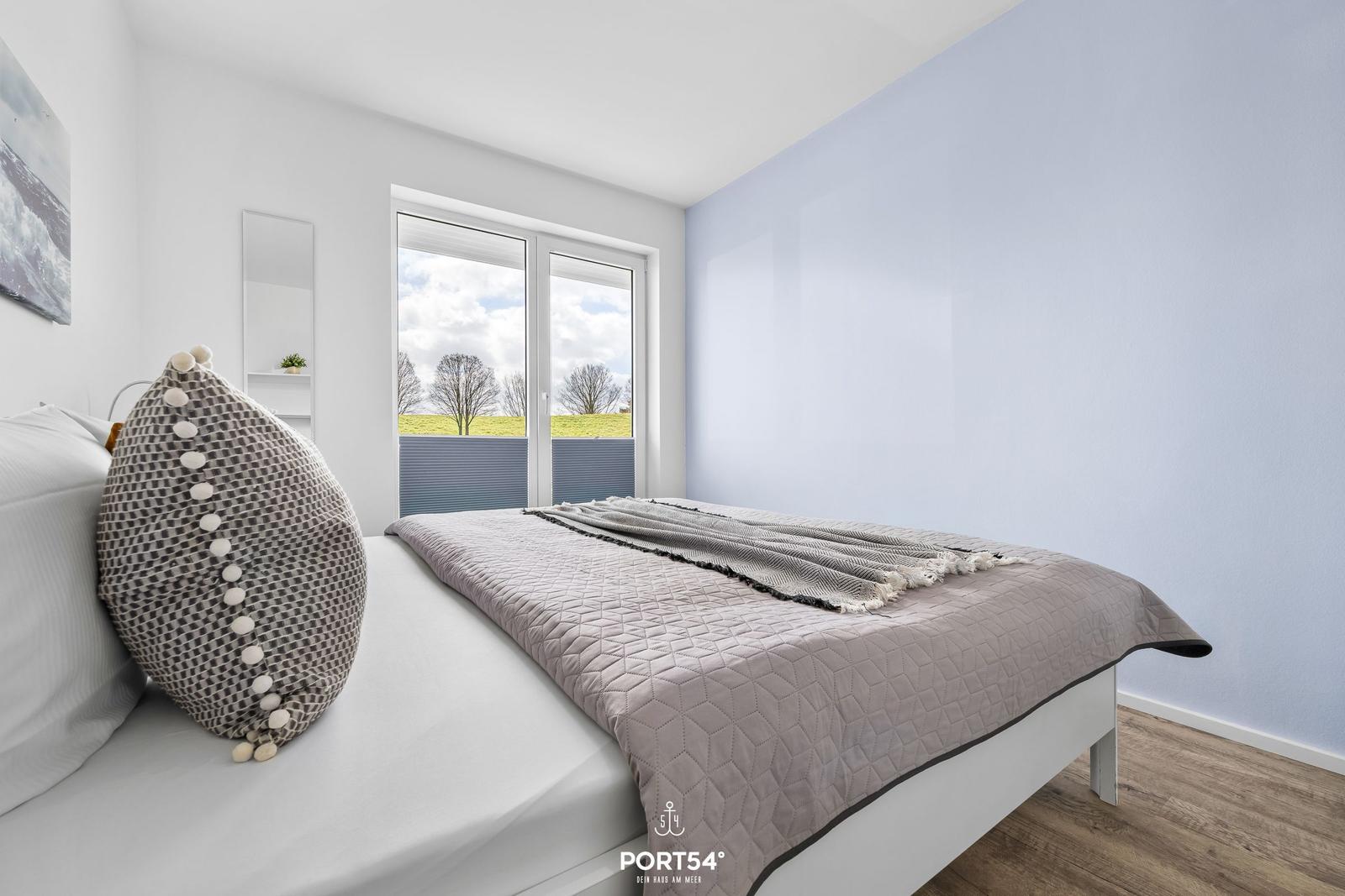 Schlafzimmer mit Bett, Fenster und Wand in Hellblau.