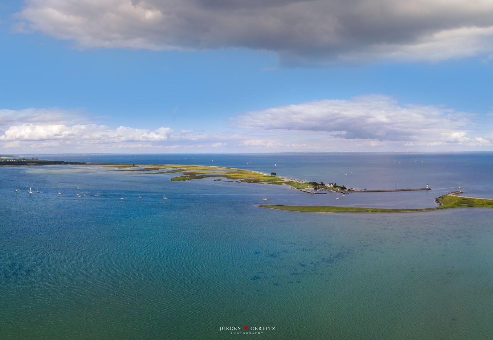 Aerial view of coastal landscape with islands, water, and boats under partly cloudy sky.