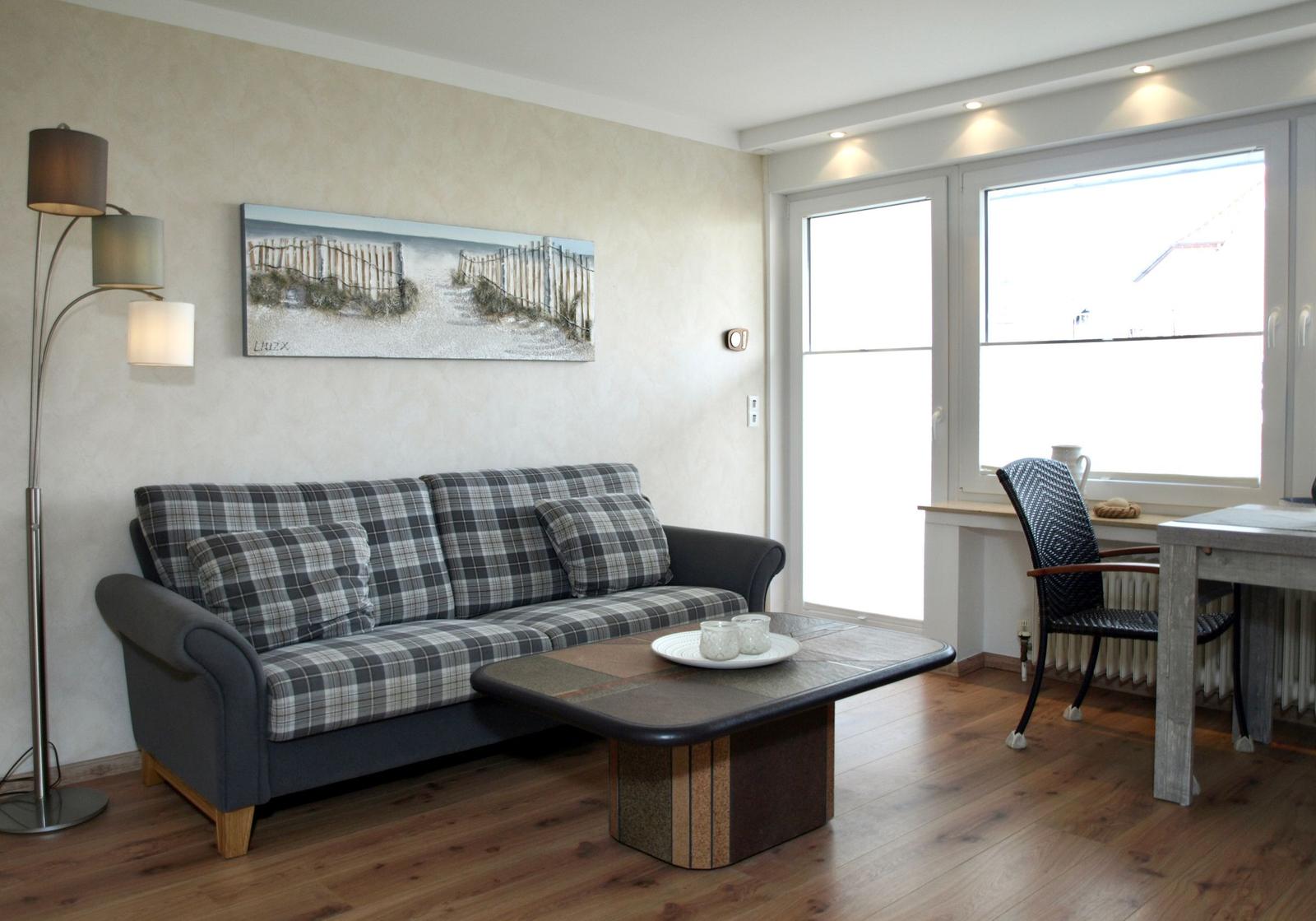 Wohnzimmer mit Sofa, Couchtisch und Fenster. Wandbild und Stehlampe sind sichtbar.