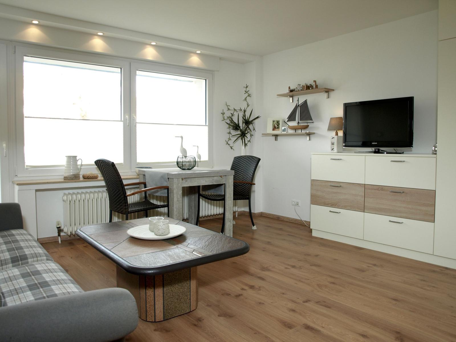 Wohnzimmer mit Esstisch, Sofa, Fernseher und Holzboden.