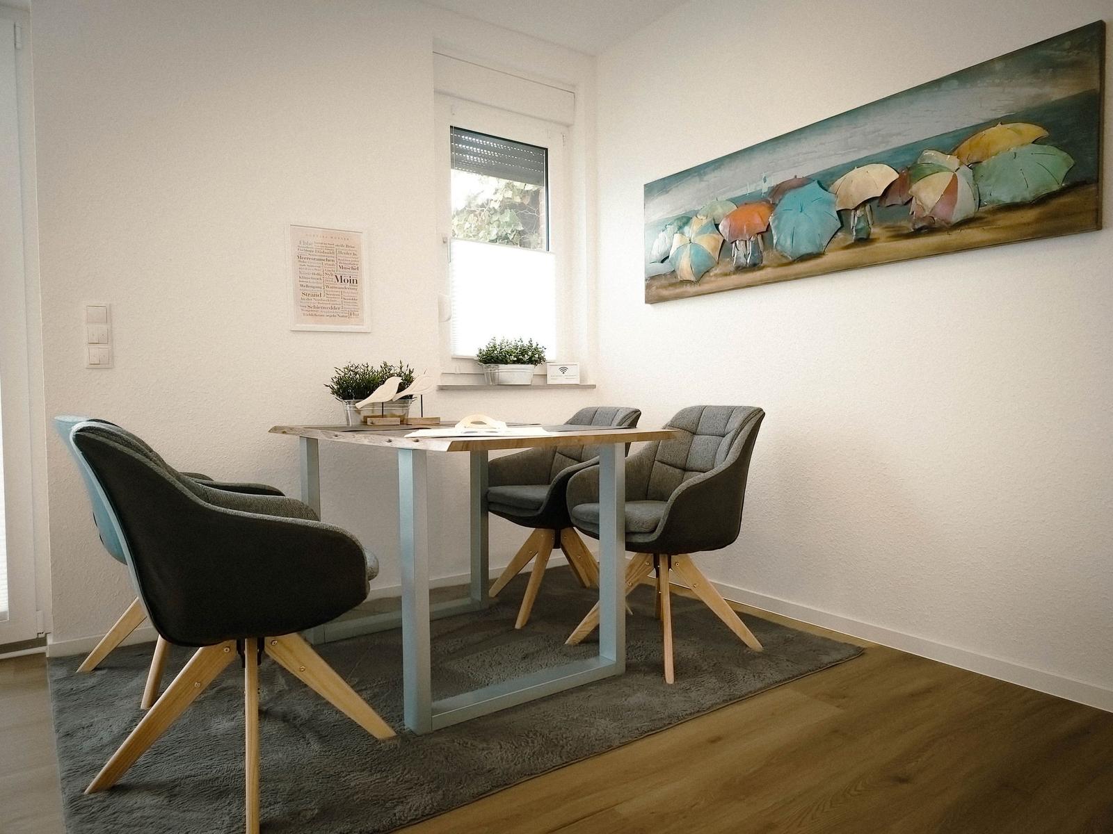 Dining room with table, four chairs, and wall art featuring umbrellas.