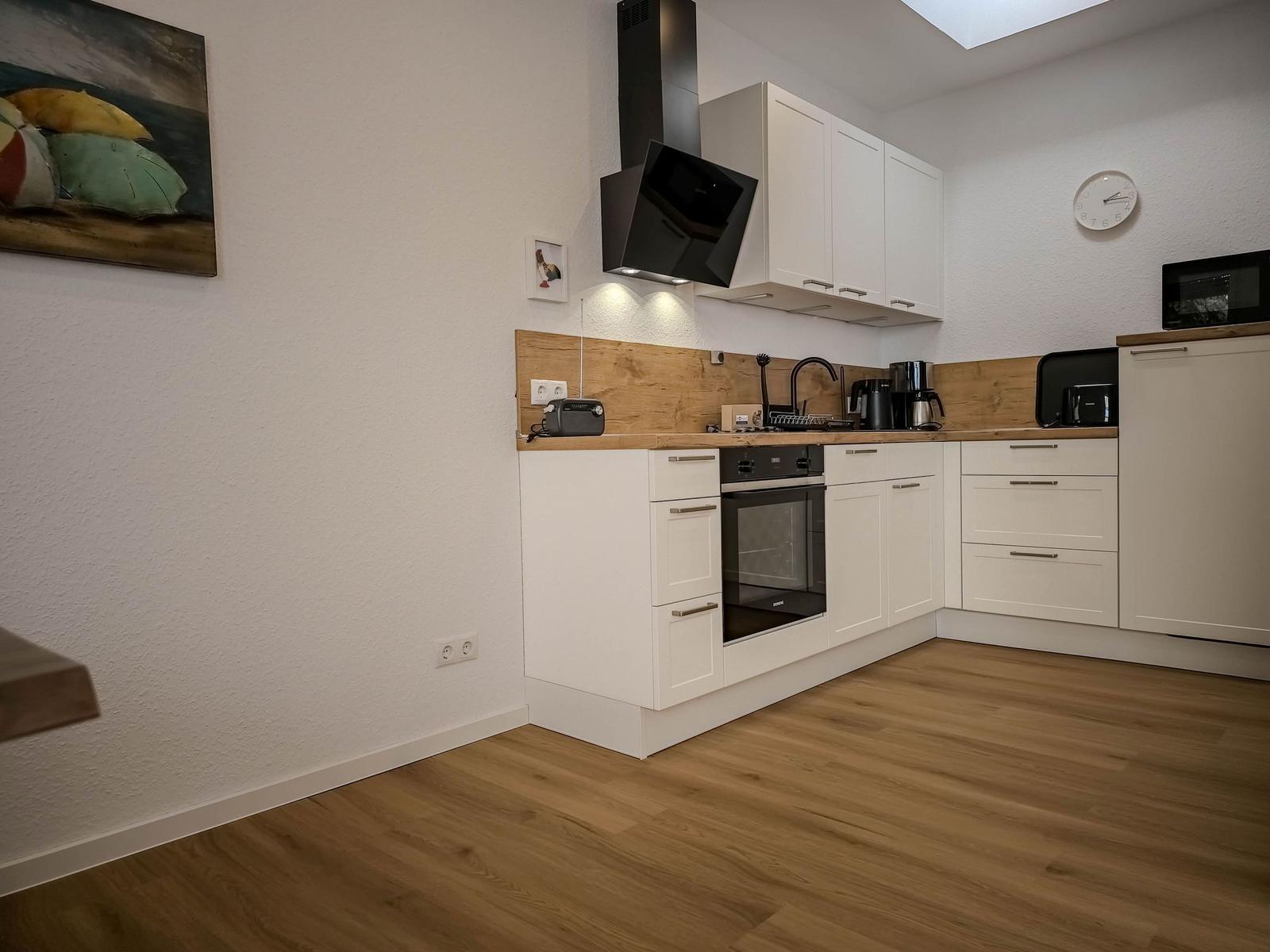 Kitchen with white cabinets, wooden countertop, and built-in oven.
