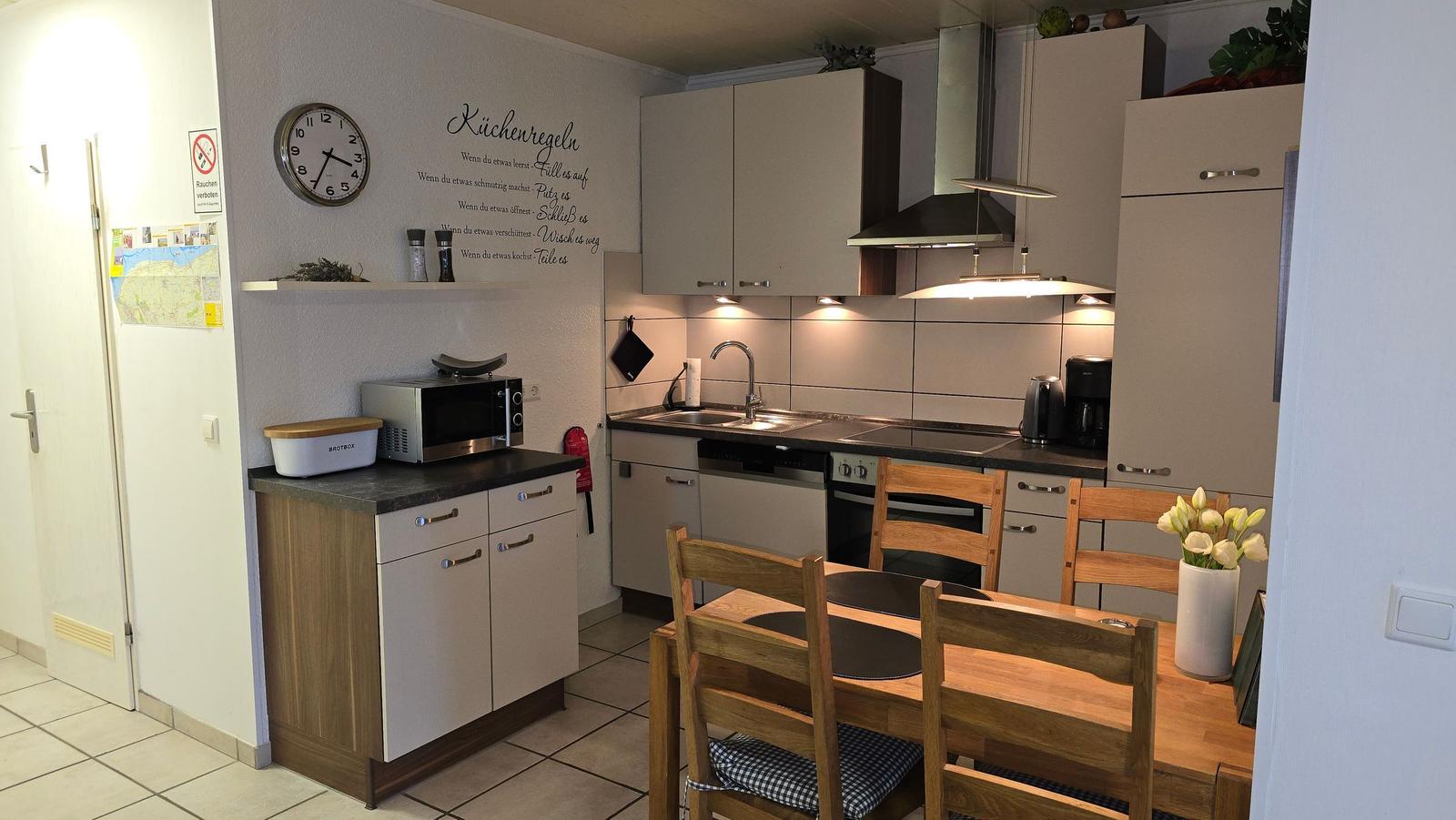 Küche mit Essbereich, Holztisch, Stühle, Küchenschränke und Arbeitsfläche.