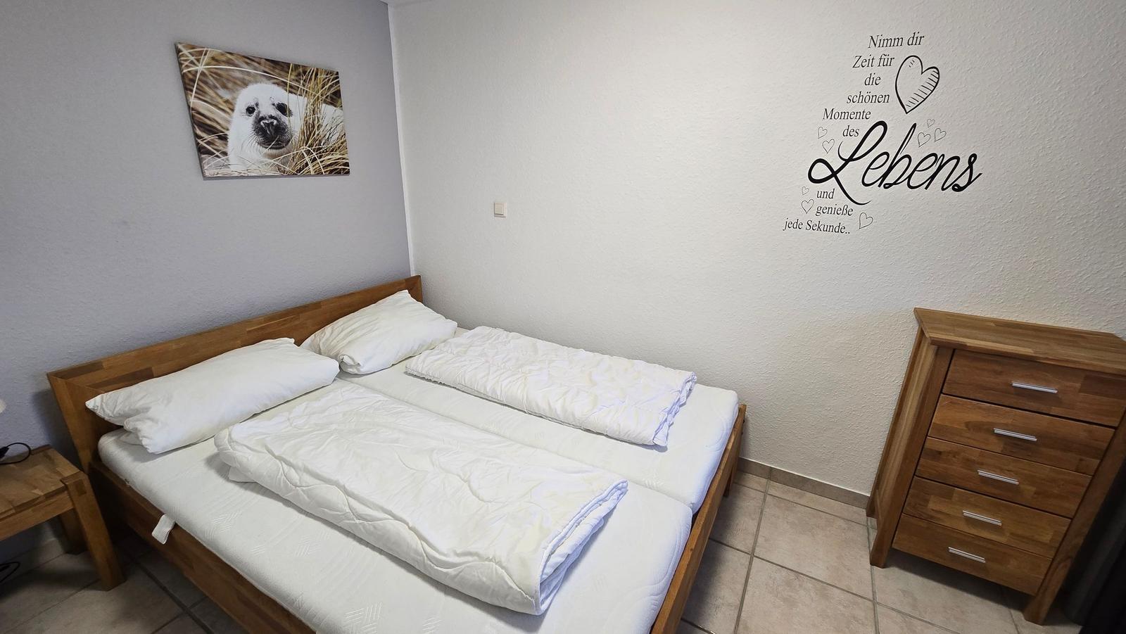 Schlafzimmer mit Doppelbett, Holzmöbel und Wanddekoration.