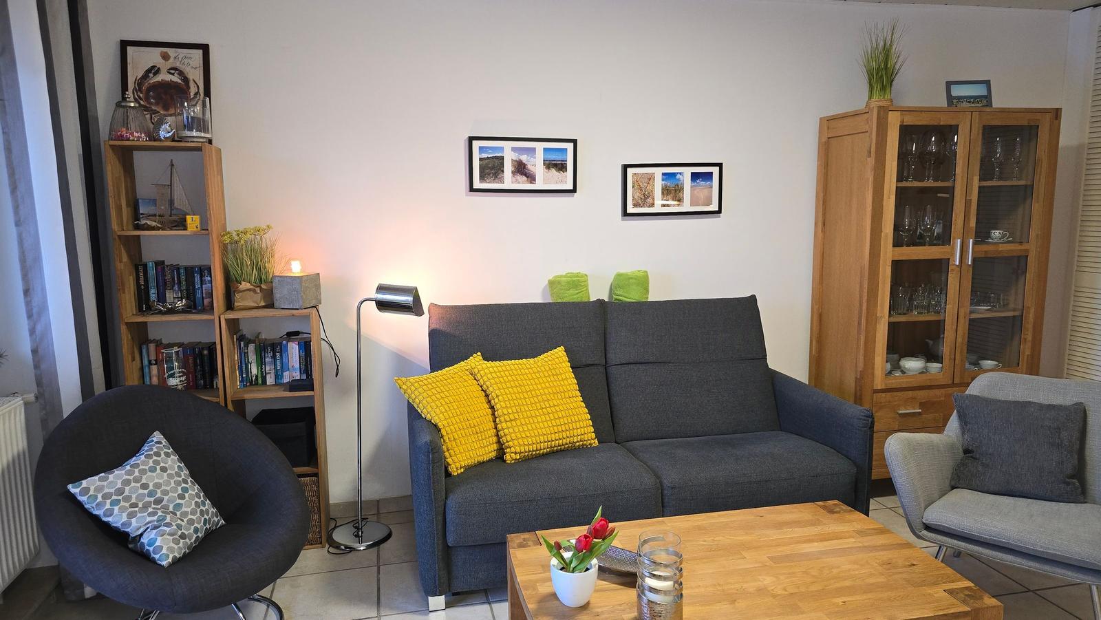 Ein Wohnzimmer mit grauem Sofa, gelben Kissen und Holztisch.