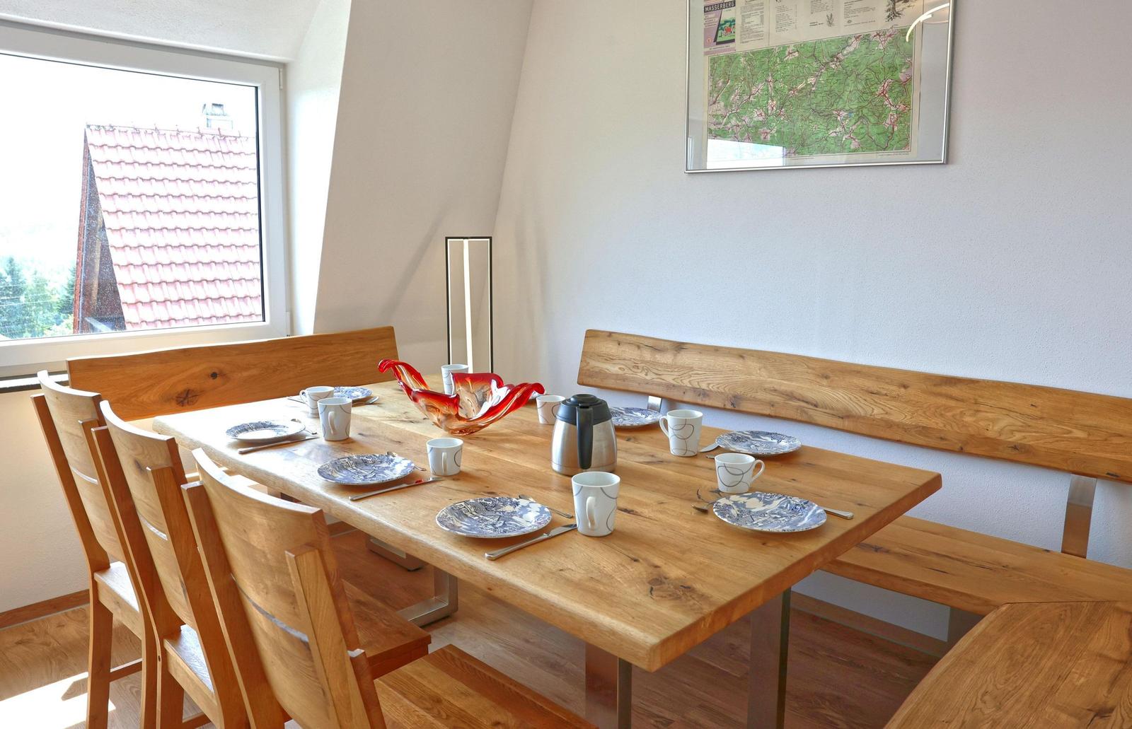 Esszimmer mit Holztisch, Bänken und Fensterblick auf Dach