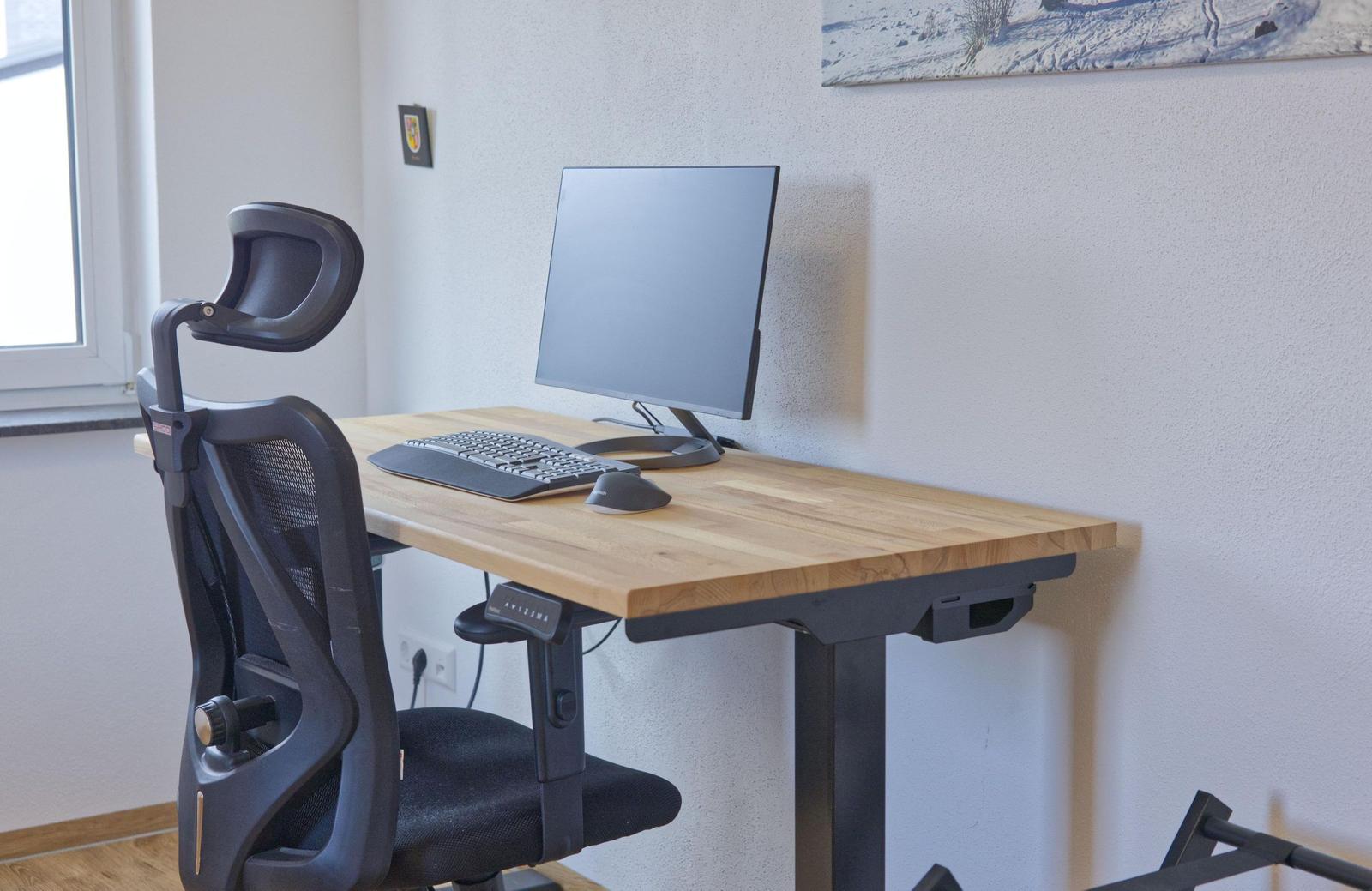 Arbeitsplatz mit Schreibtisch, Monitor, Tastatur und ergonomischer Sitzgelegenheit.