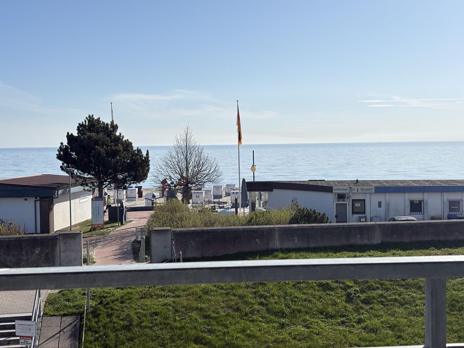 Blick auf Strand mit Strandkörben und Meer. Gebäude mit Schild Strand Olandt.