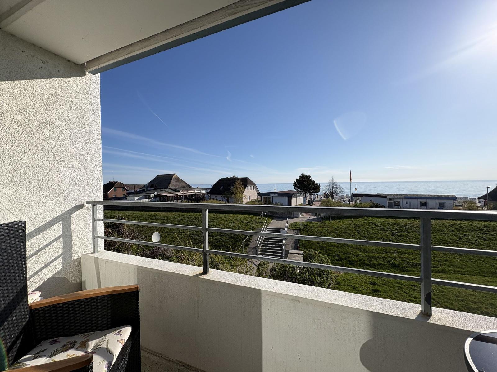 Balkon mit Sicht auf Strand und Meer unter blauem Himmel.