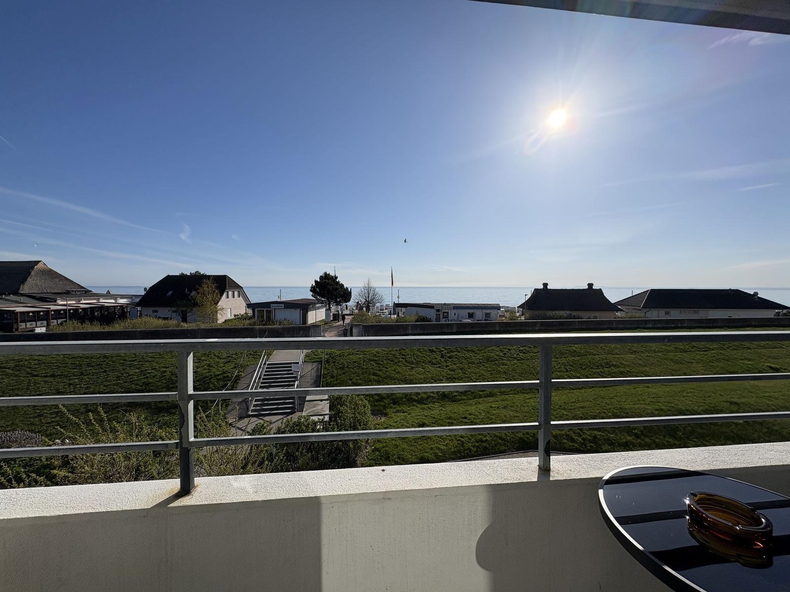 Balkon mit Blick auf den Strand und das Meer unter strahlendem Sonnenschein.