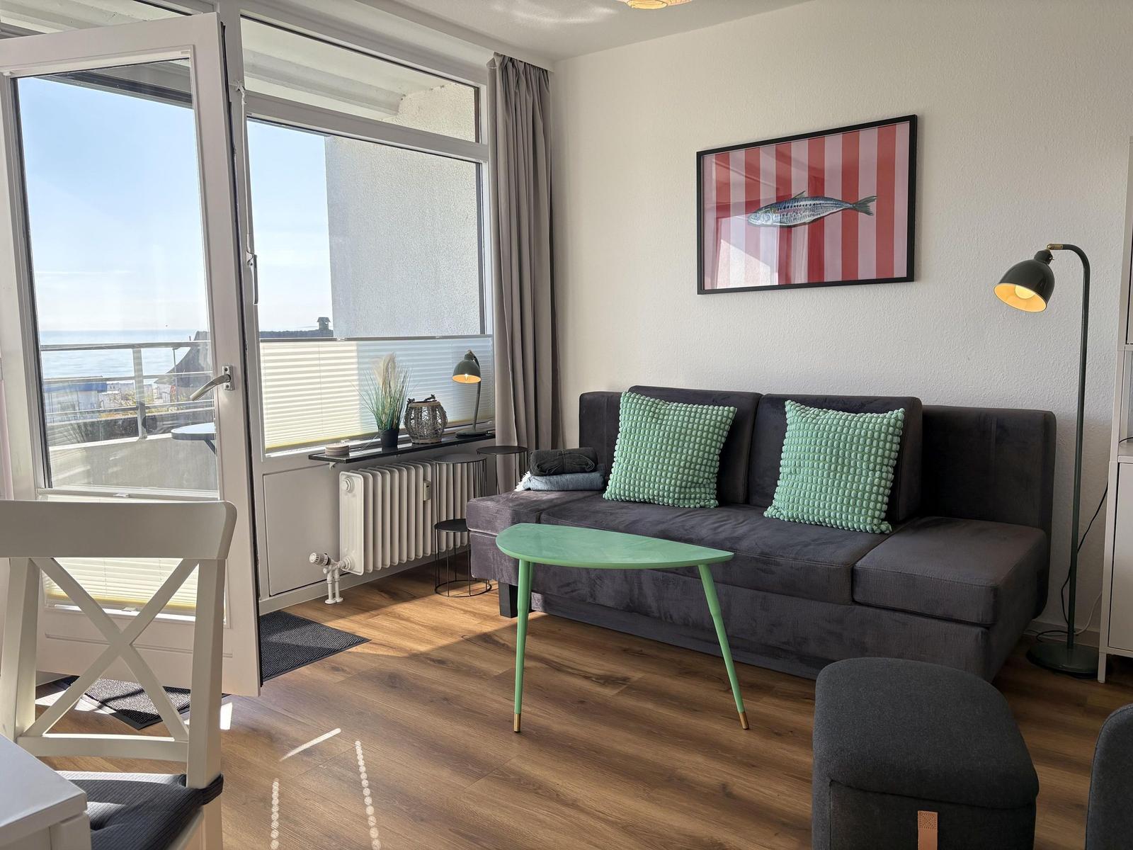 Wohnzimmer mit Sofa, Tisch und Aussicht aufs Meer.