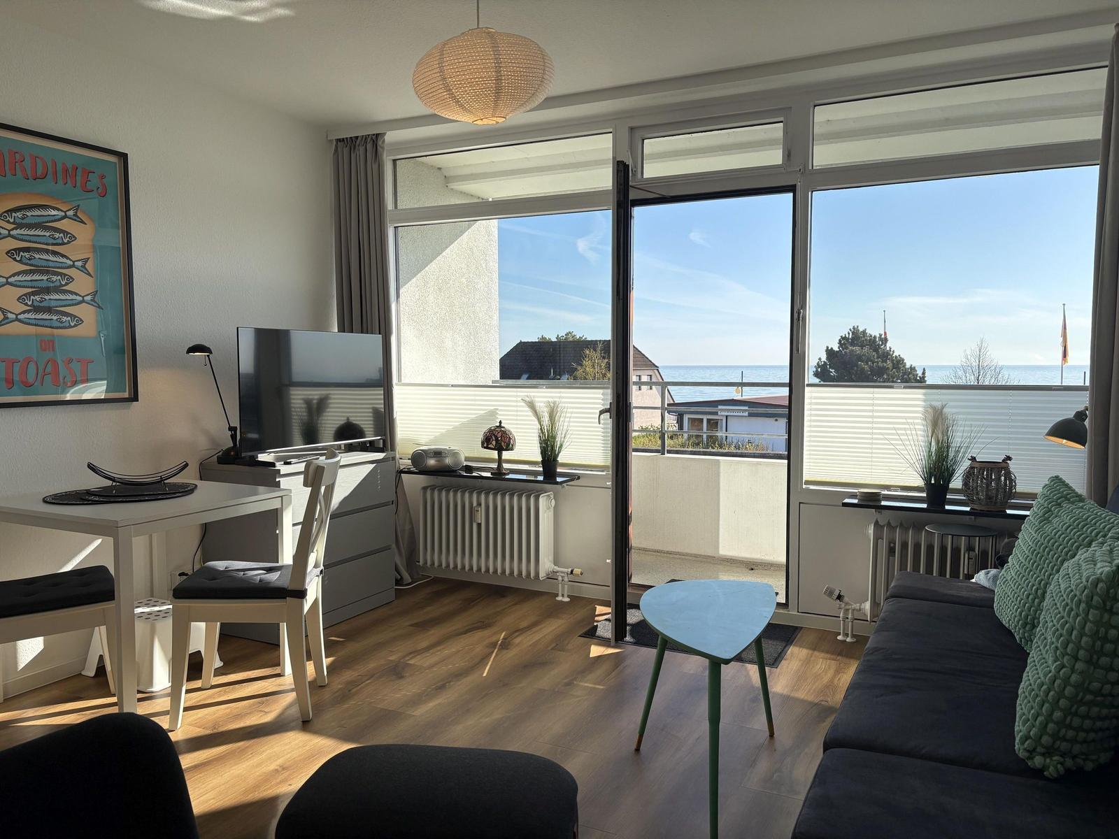 Wohnzimmer mit Balkonblick auf Meer. Möbel und Dekoration sichtbar.