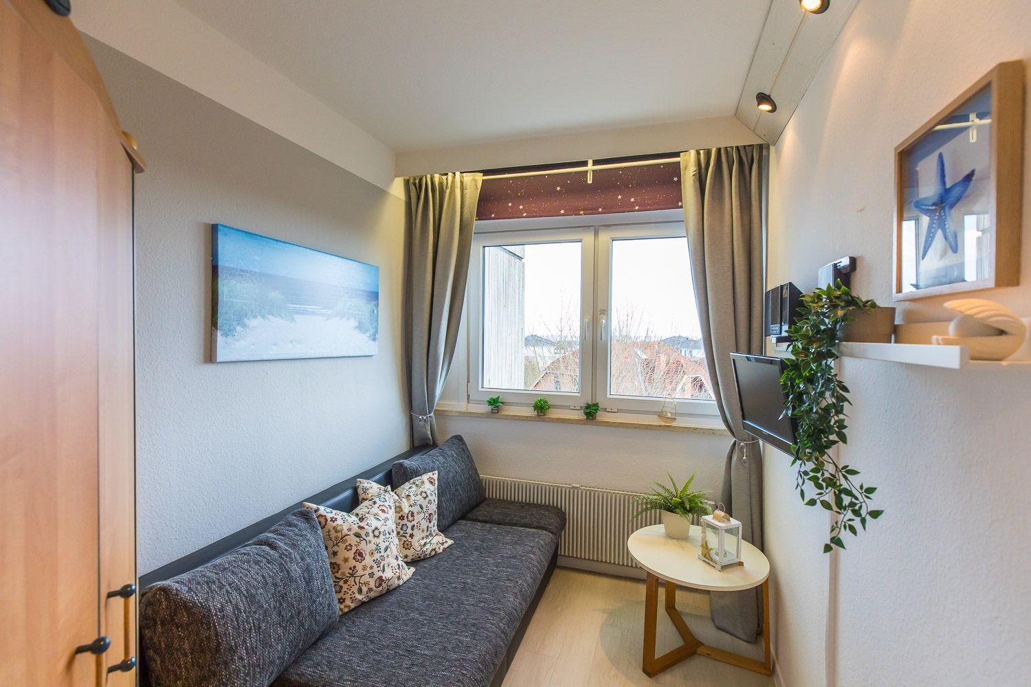Ein Wohnzimmer mit Sofa, Fenster und Wanddekoration.