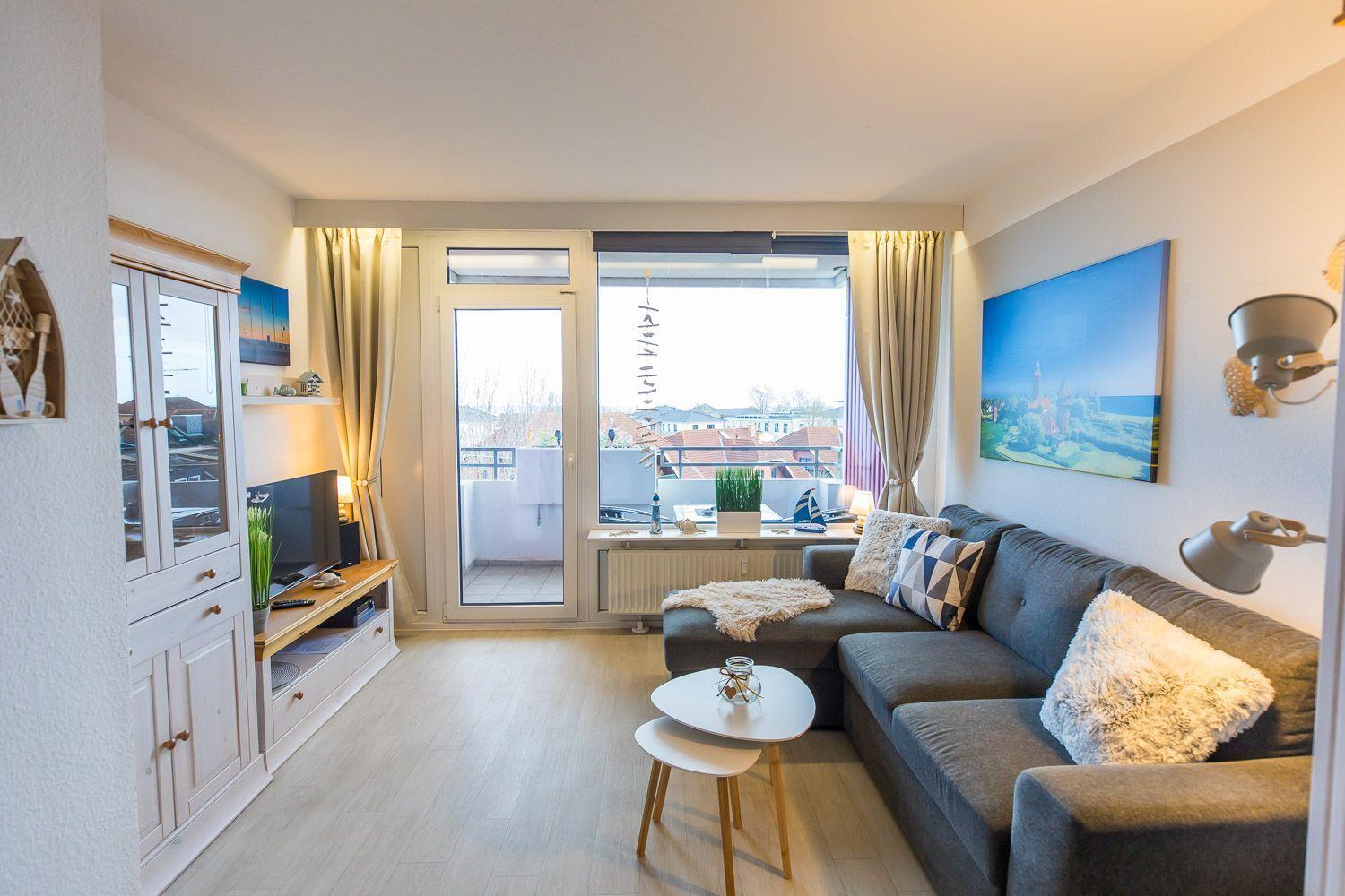 Wohnzimmer mit Sofa, Couchtisch und Balkontür. Blick auf Dächer. Wandbild und TV.