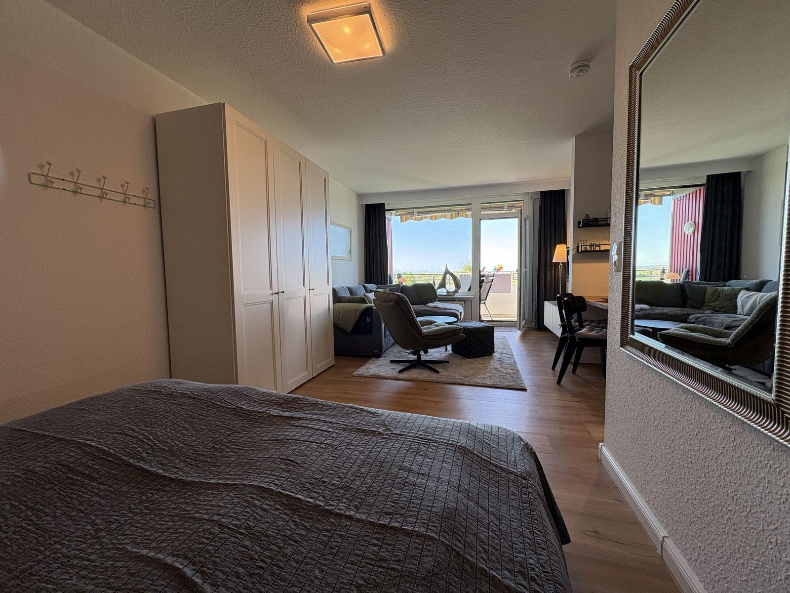 Schlafzimmer mit Blick auf Wohnbereich und Balkon mit Meerblick.