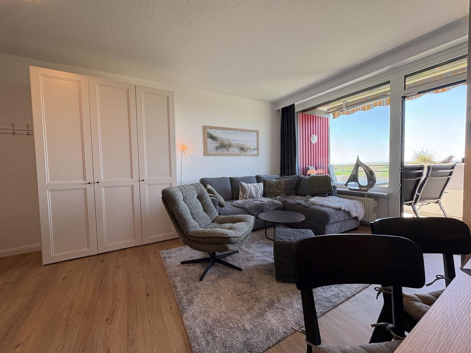Wohnzimmer mit Sofa, Sessel und Blick auf Balkon