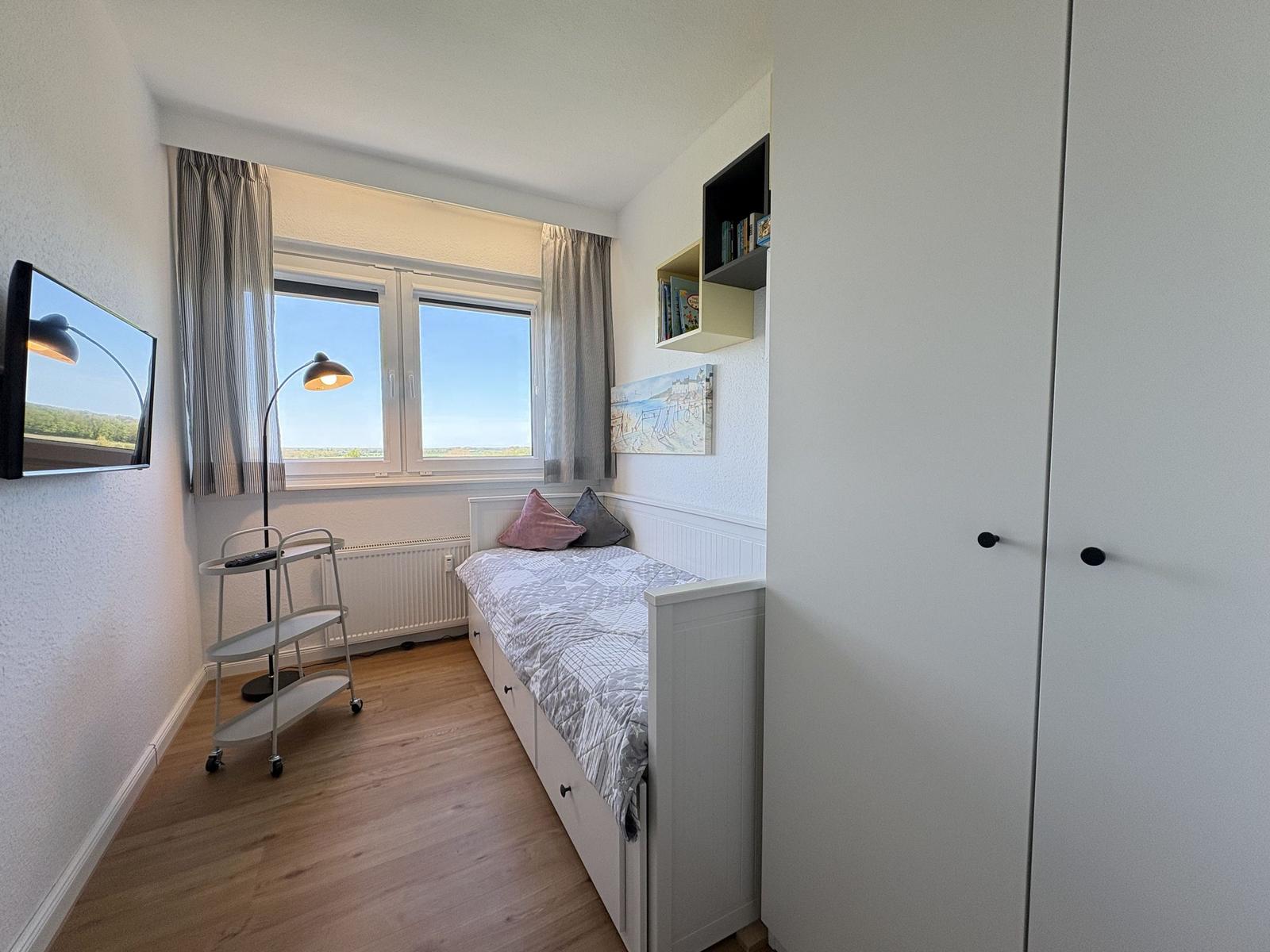 Schlafzimmer mit Bett, Schrank und Fenster mit Blick. Wandbild und TV.