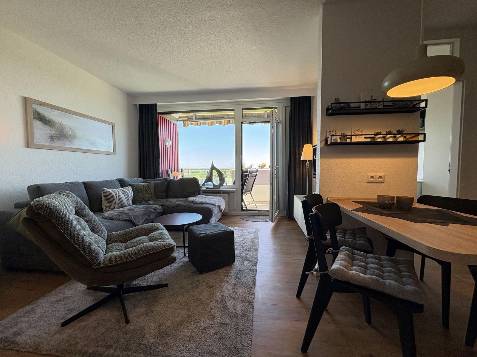 Wohn- und Essbereich mit Balkon und moderner Einrichtung.