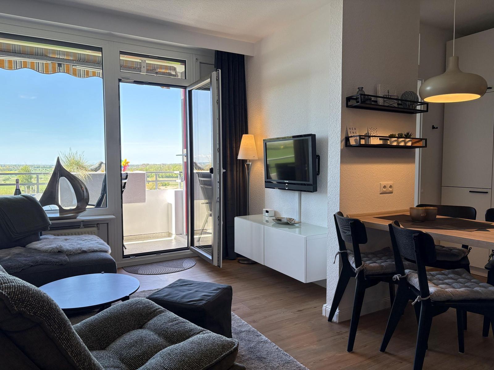 Wohnbereich mit TV, Esstisch und Balkon mit Aussicht.