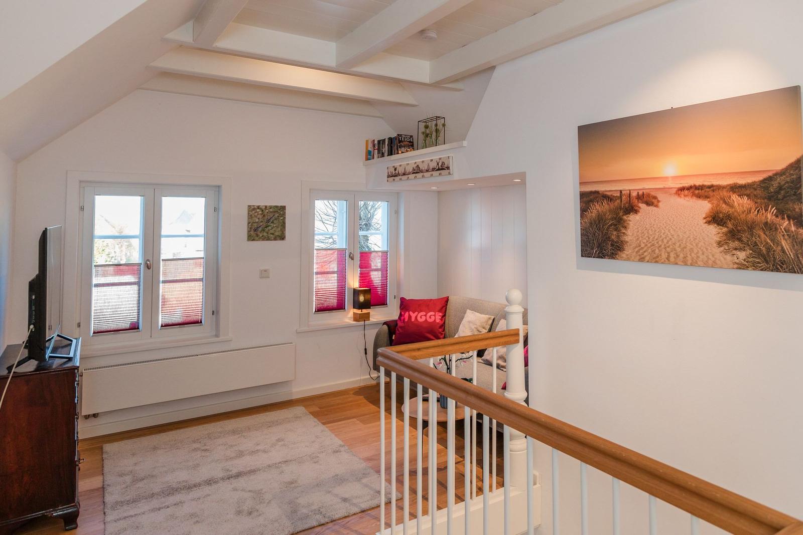 Wohnbereich mit Holzboden, TV, Fenstern und Wandbild