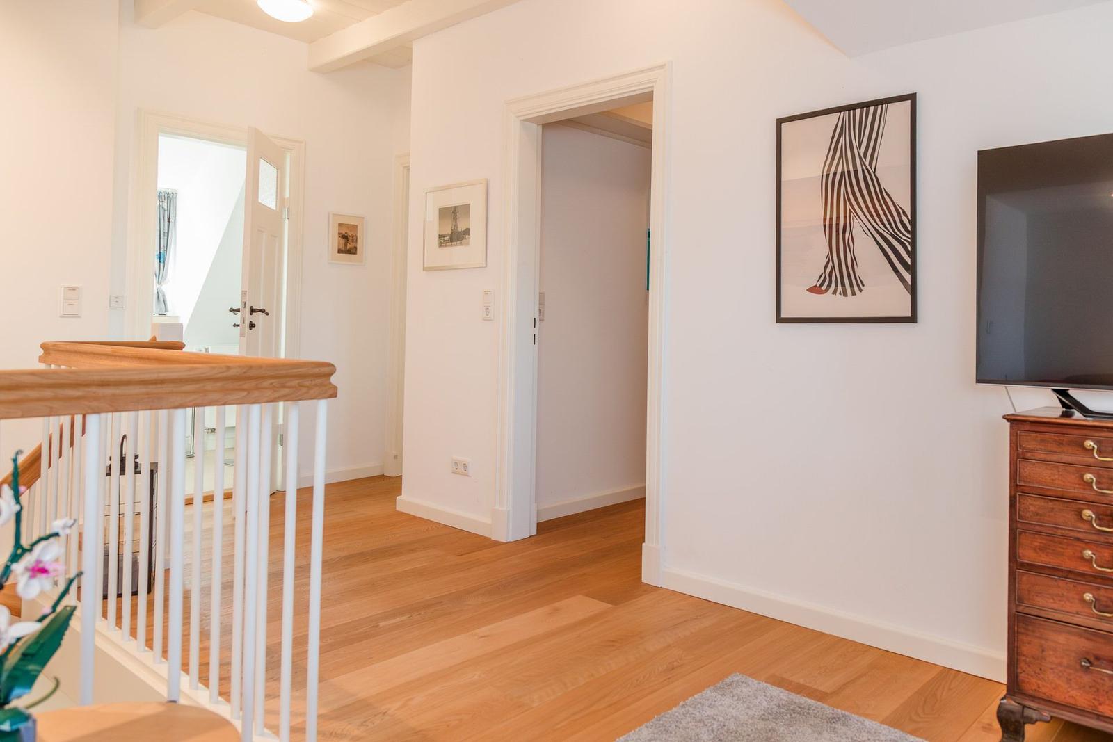 Helle Wohnung mit Holzboden, Wandbild und Fernseher auf Schrank