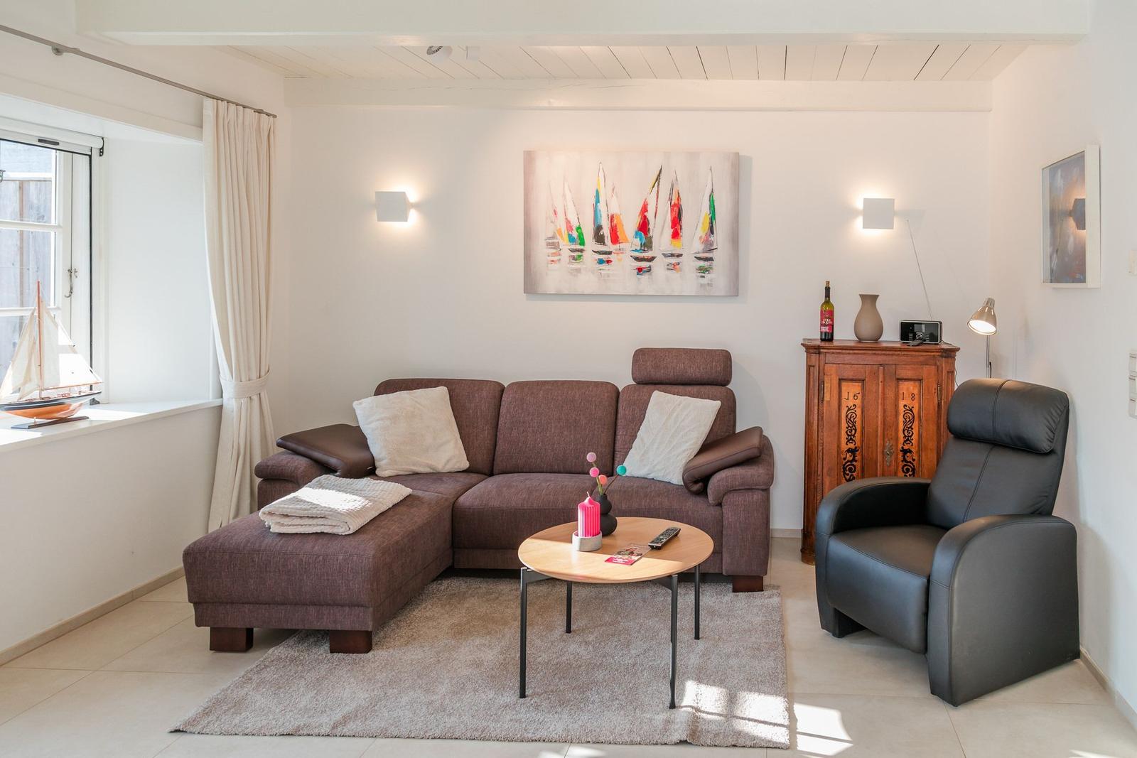Ein Wohnzimmer mit braunem Sofa, schwarzer Ledercouch und Holzkommode.