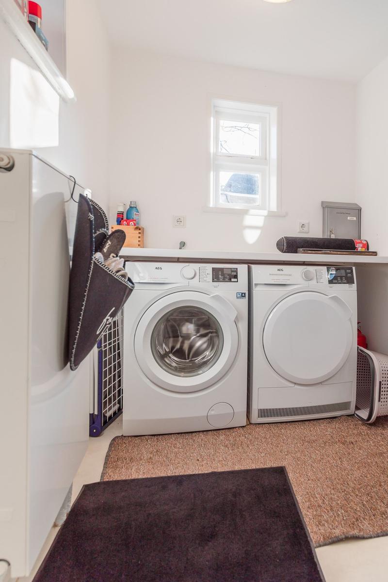 Wäscherei mit Waschmaschine und Trockner, Fenster und Bodenteppich.