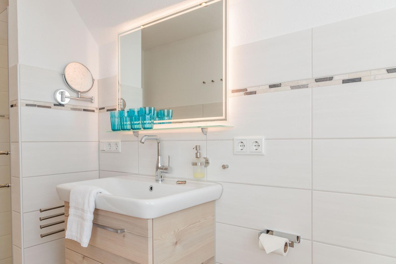 Badezimmer mit Waschbecken, Spiegel und Handtuchhalter.
