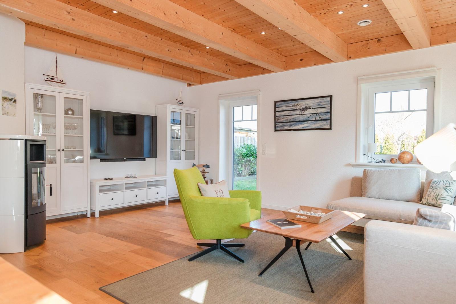 Wohnzimmer mit Holzboden, grüner Sessel und Fernseher an der Wand.