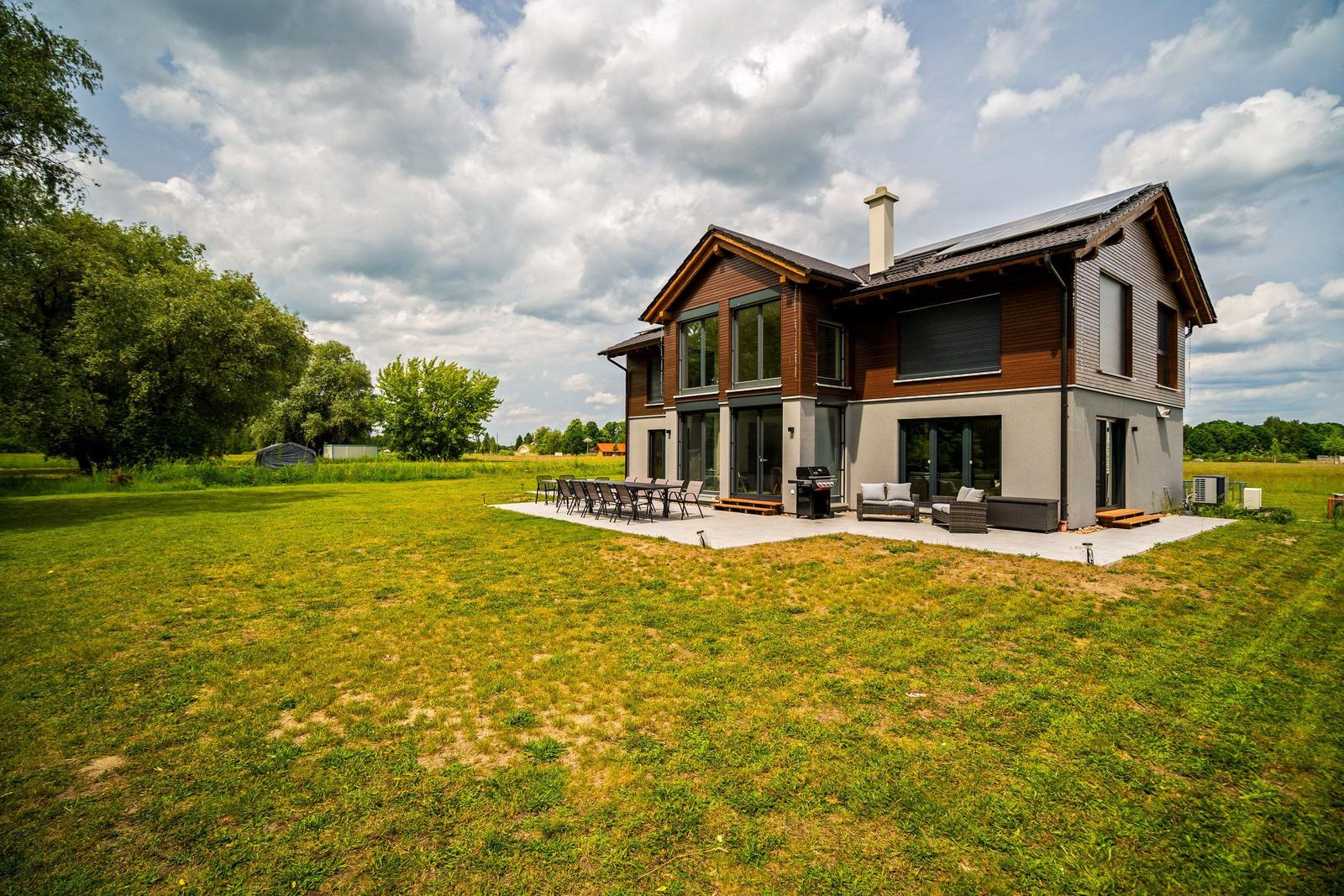 Moderne Villa mit großem Garten und Terrasse mit Sitzgelegenheiten.