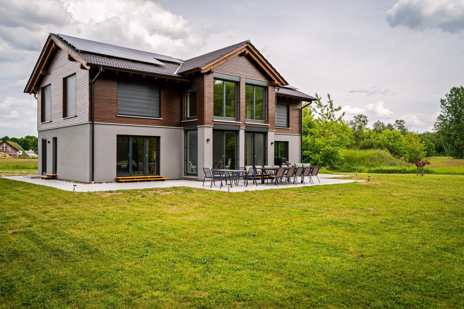 Moderne Villa mit Solaranlage und großem Garten. Außenterrasse mit Tisch und Stühlen.