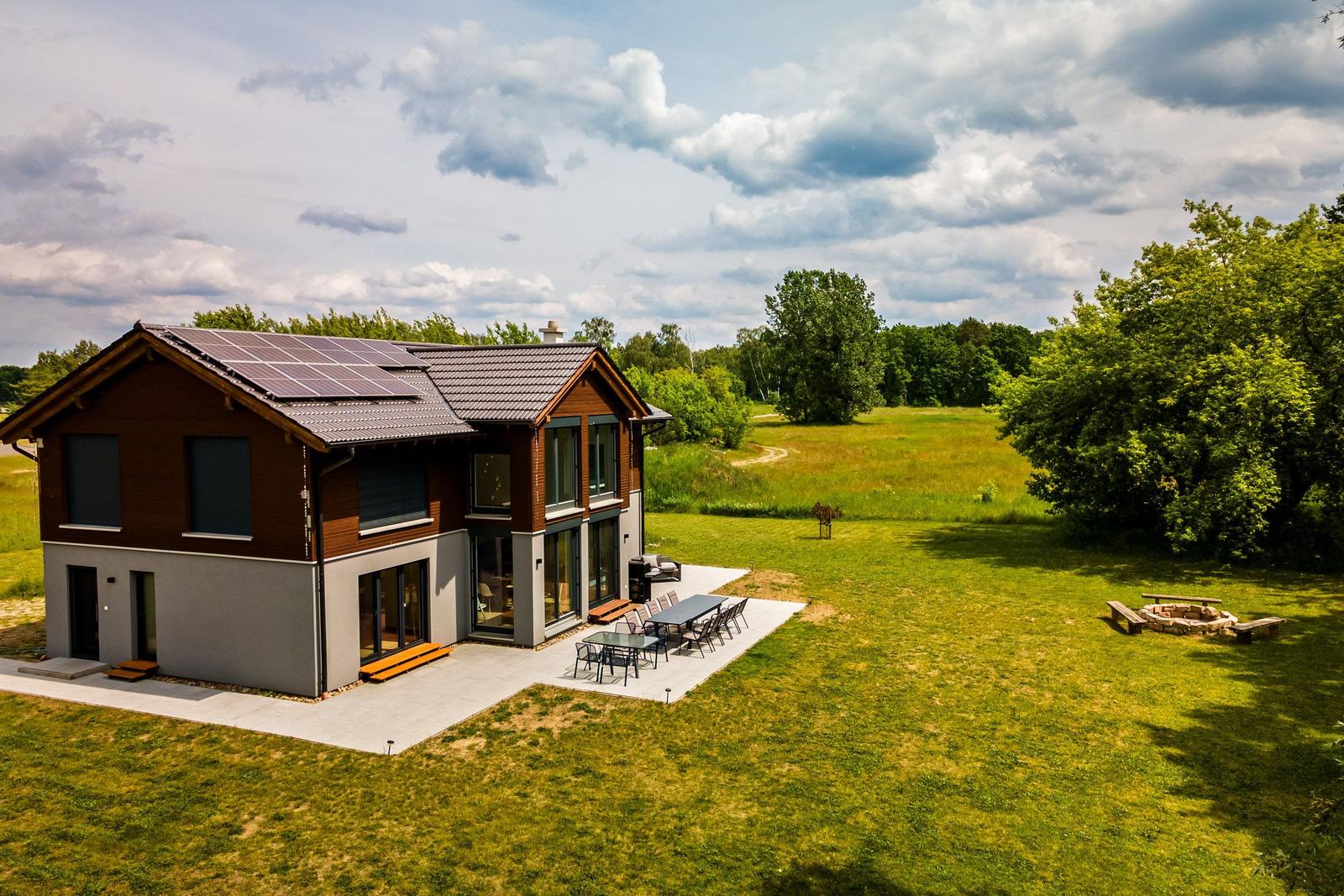 Modernes Haus mit Solaranlage, großem Garten und Grillplatz. Terrasse mit Tisch und Stühlen.
