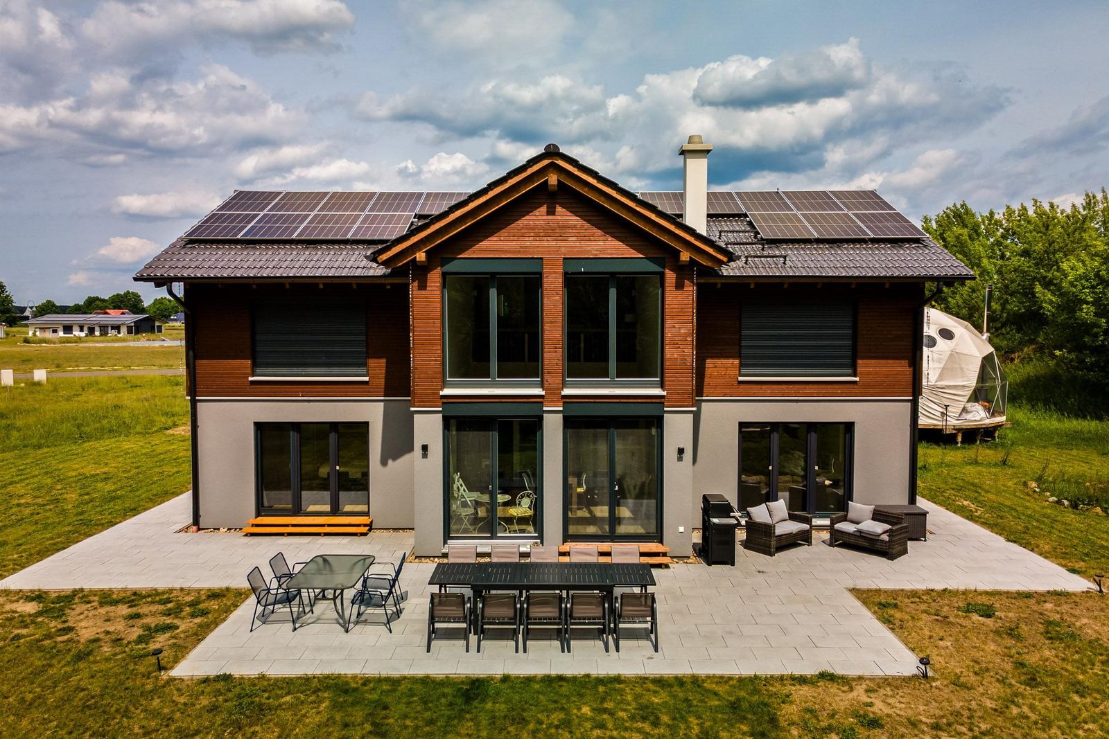 Moderne Villa mit Solaranlage und großem Außenbereich mit Sitzgelegenheiten.