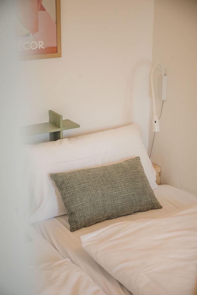 Bettkopfteil mit Kissen, Wandlampe und Bild an der Wand