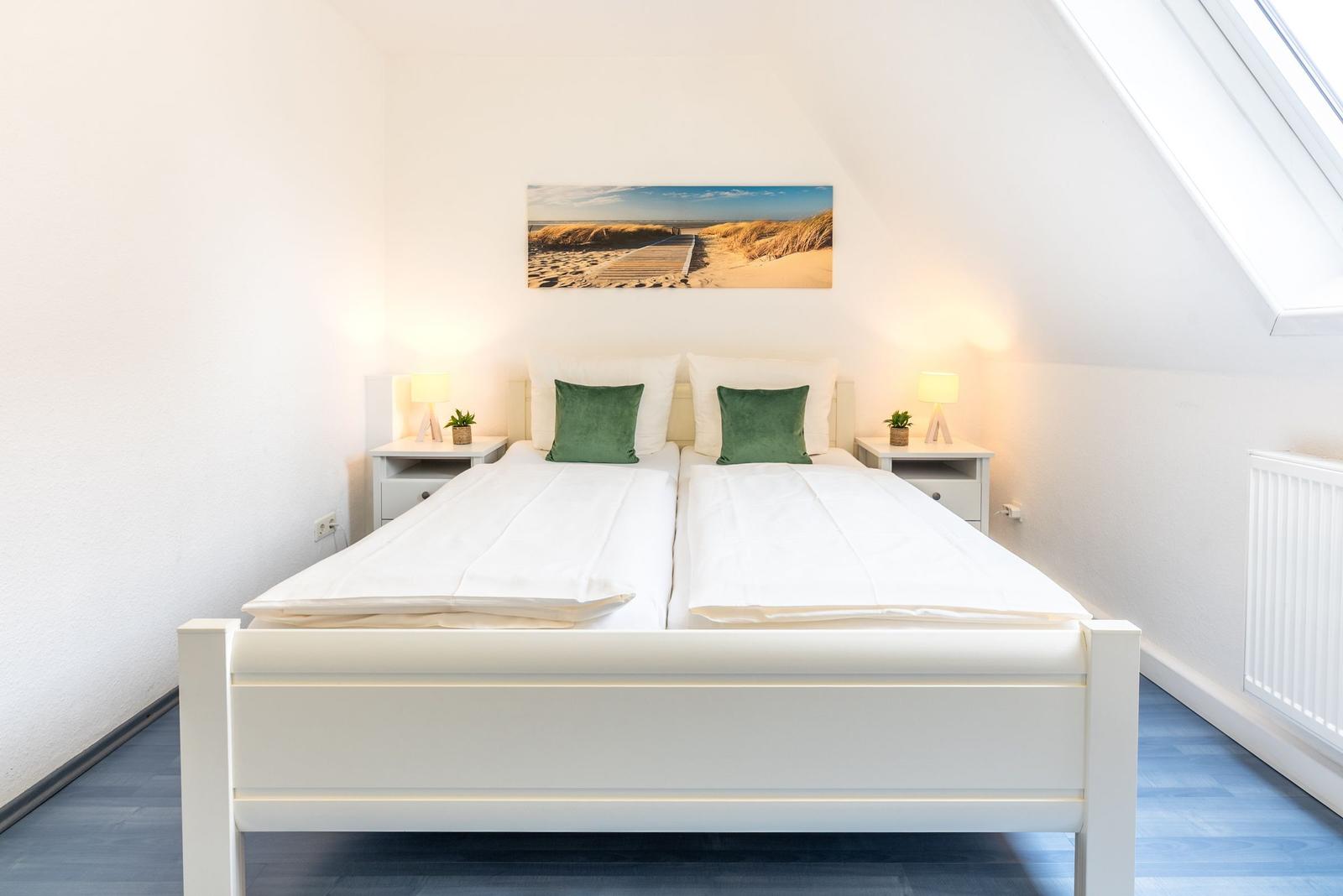 Schlafzimmer mit Doppelbett, zwei Nachttischen und Dachschrägenfenster.