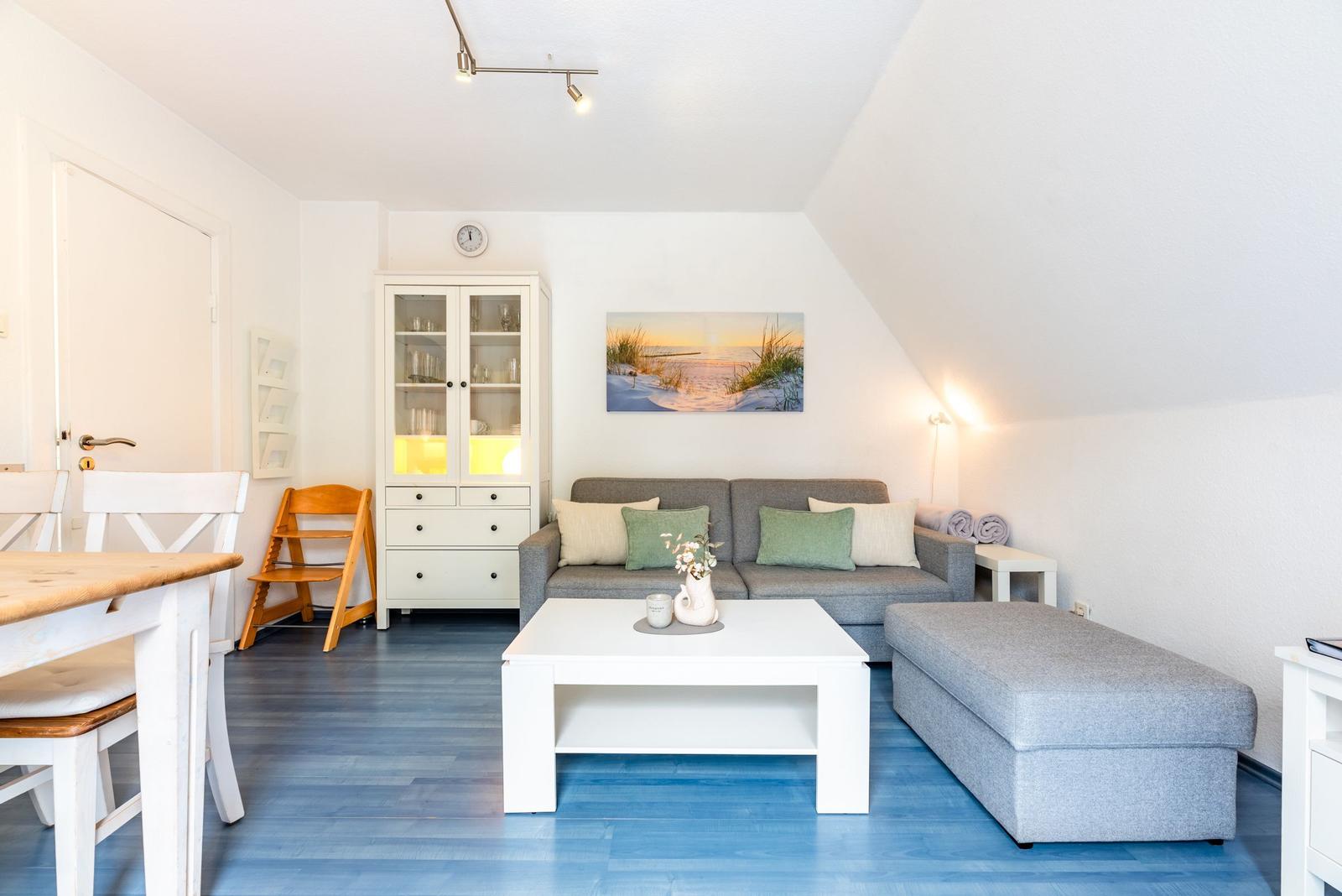 Wohnbereich mit Sofa, Couchtisch und Glasvitrine unter schrägen Decken.