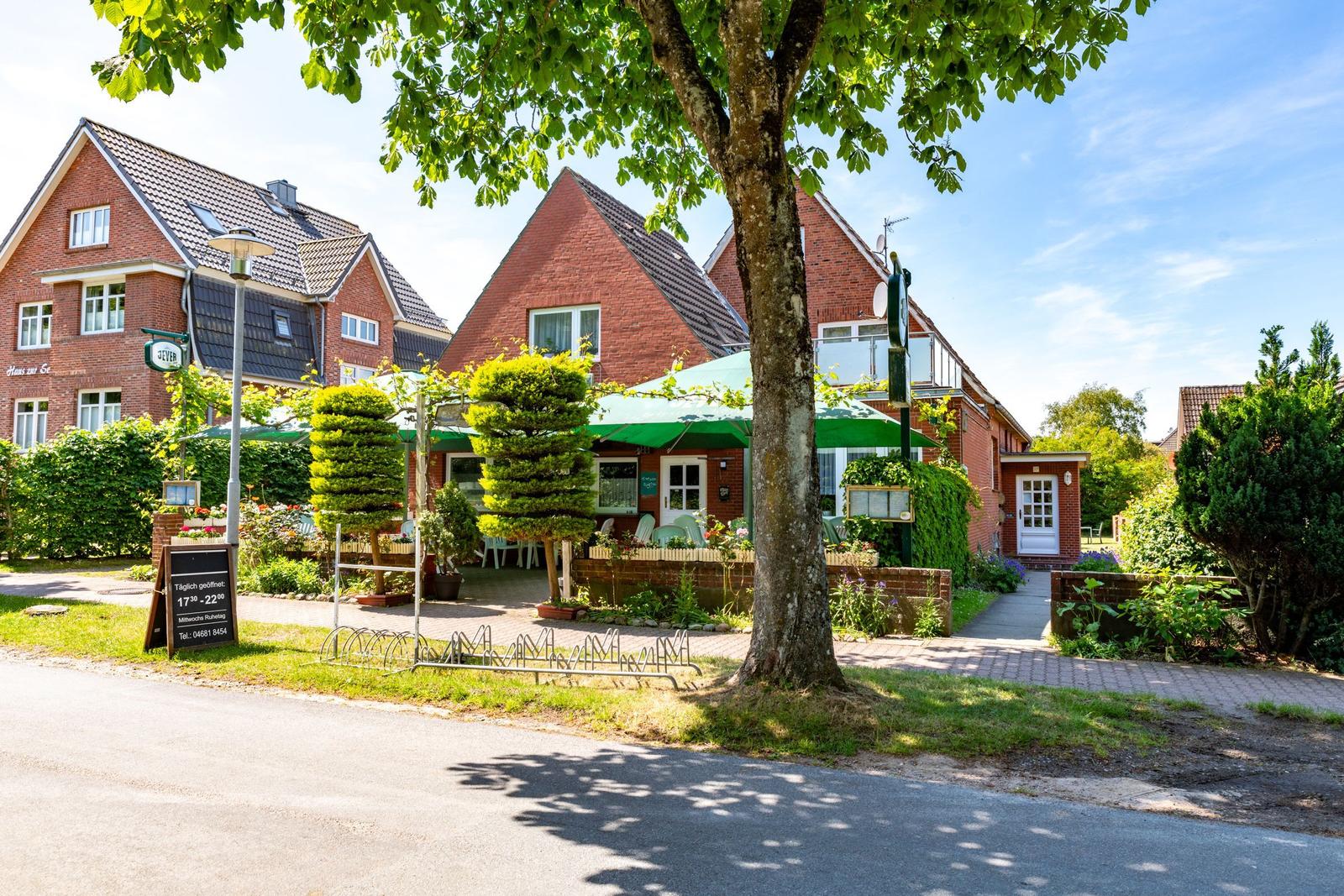 Rotes Backsteingebäude mit grünem Markisenausschlag und gepflegtem Gartenbereich.