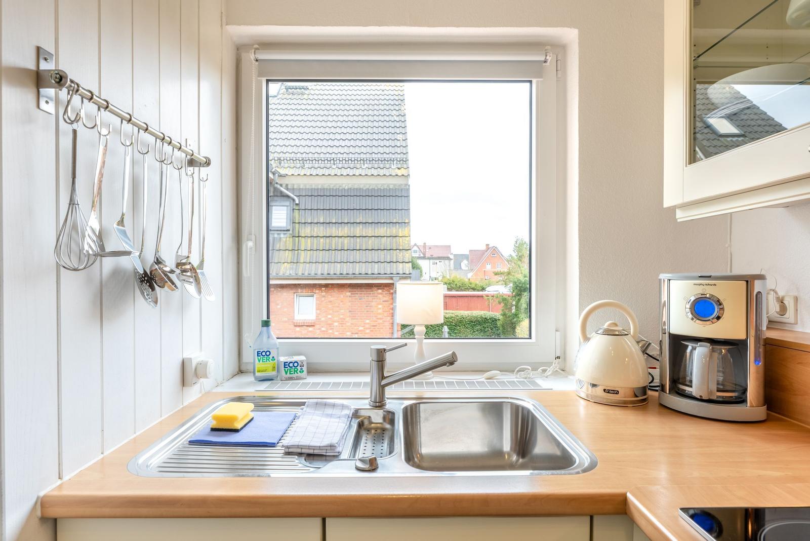 Küche mit Spüle, Fenster und Küchengeräten.